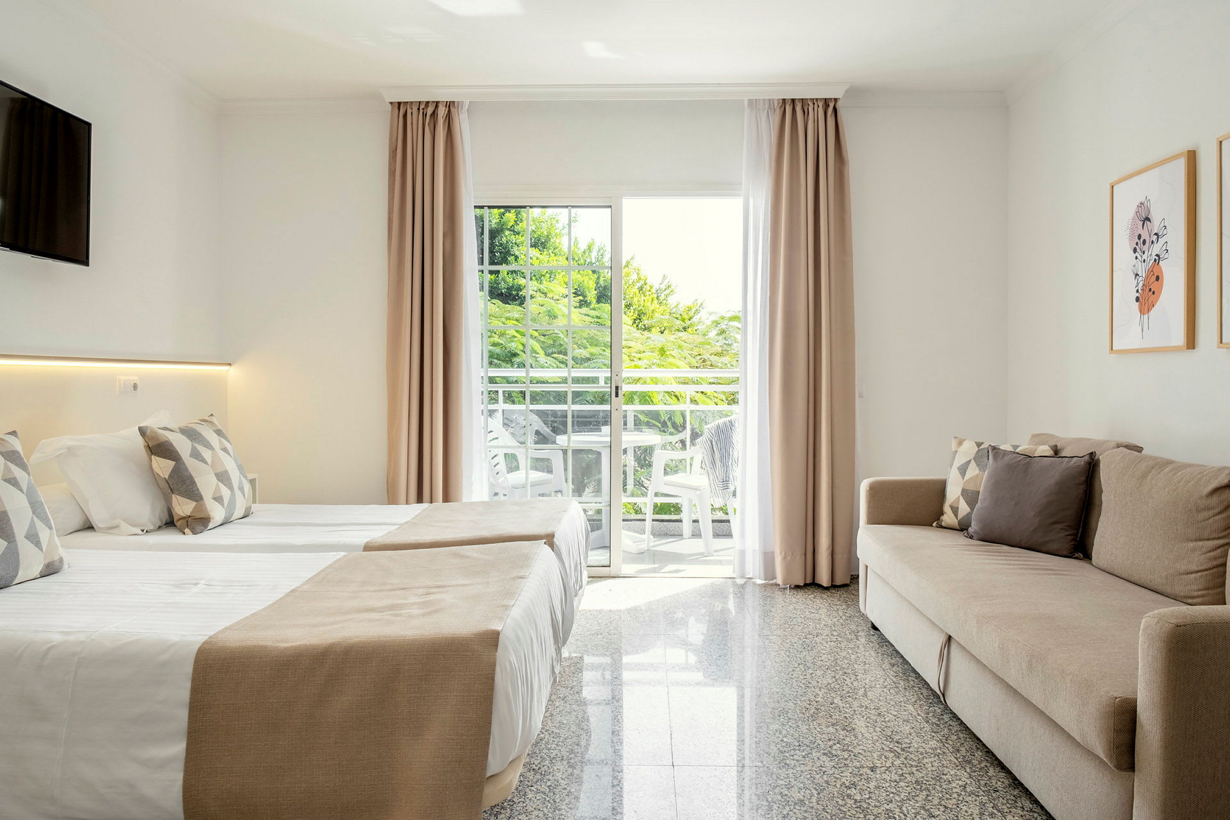 Modern hotellrum interiör med en bäddsoffa, två sängar, och en balkong med utsikt. (AI-genererad text)