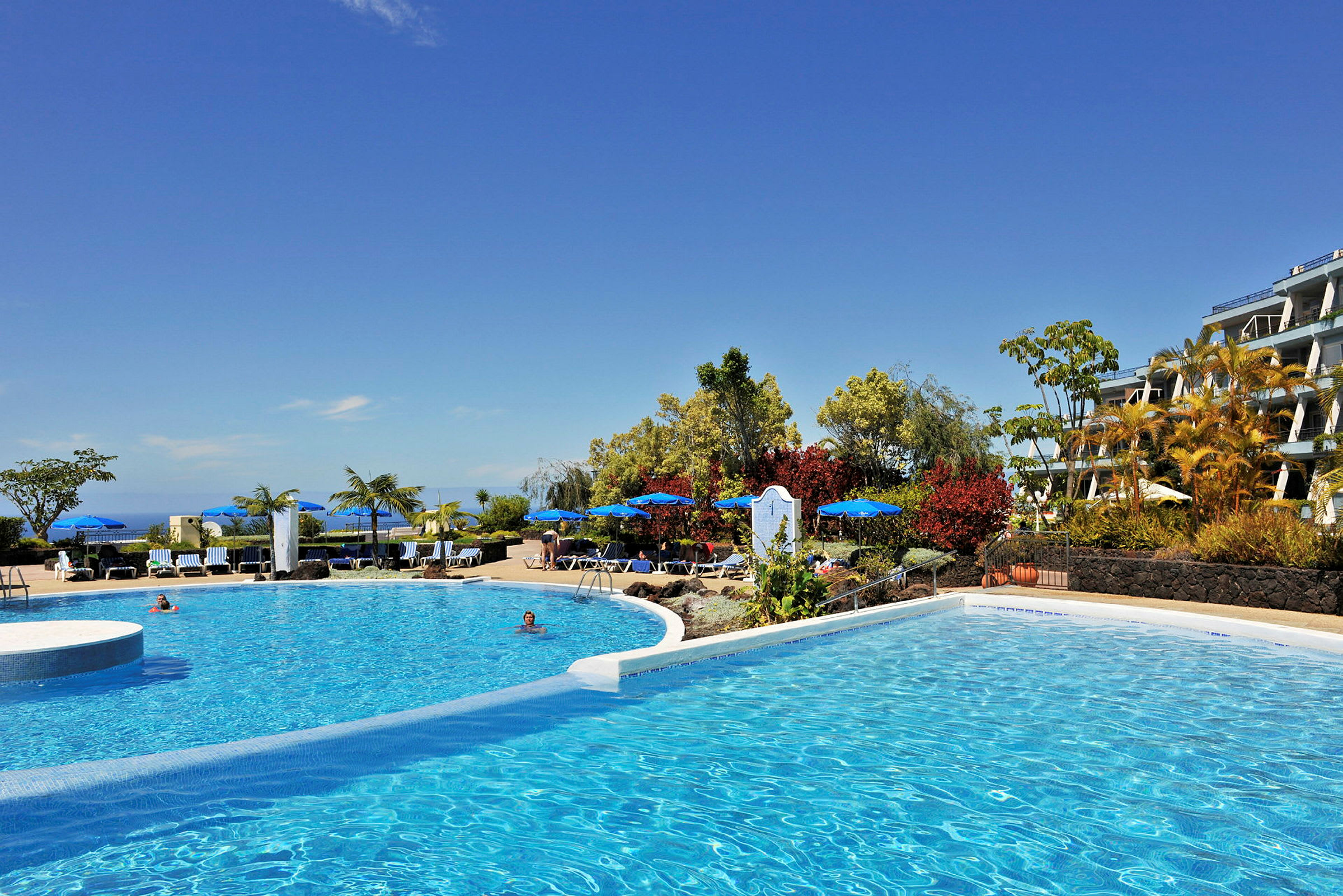 Bild av en pool vid ett hotell med solstolar och parasoller. (AI-genererad text)