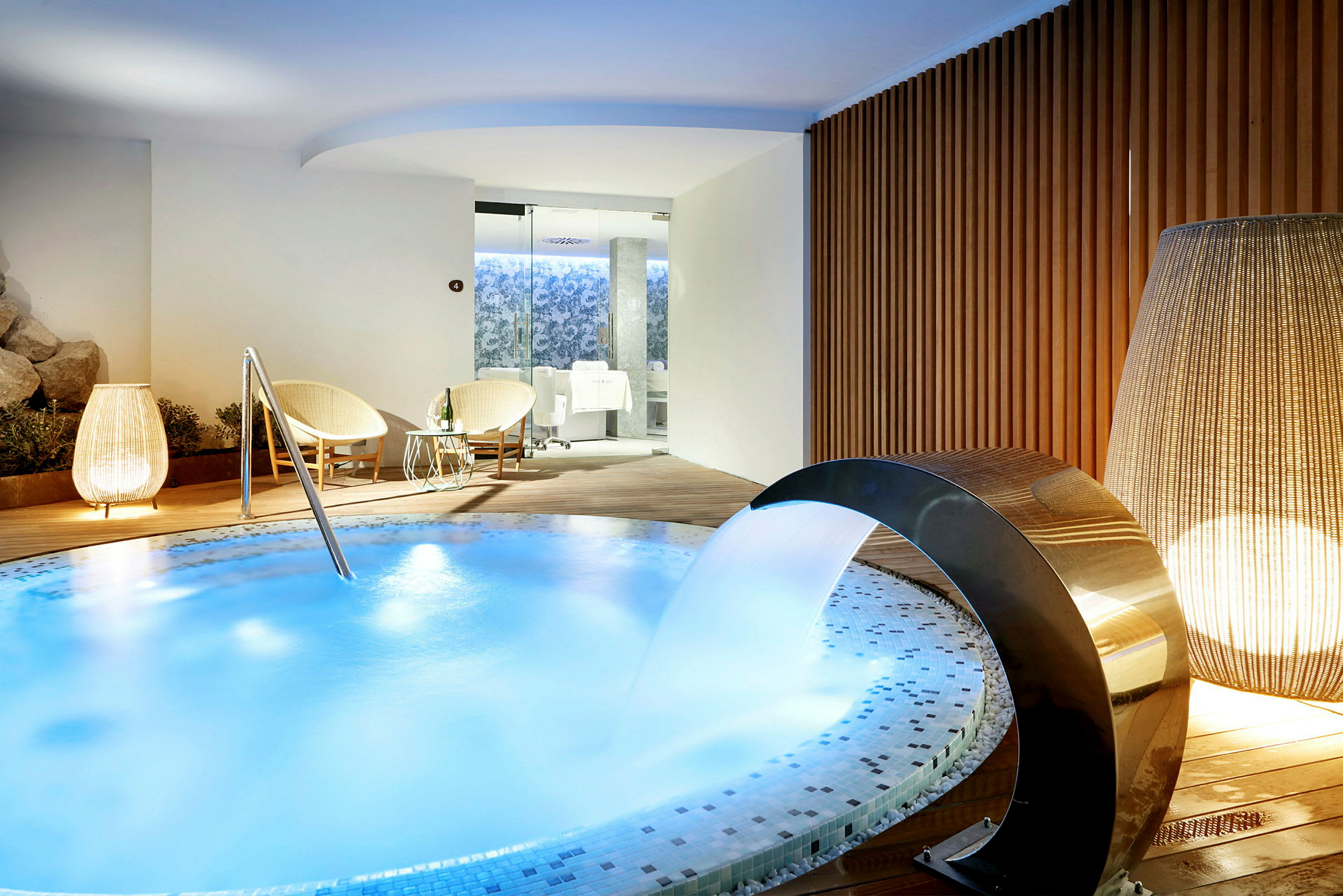 Ett spaområde med en bubbelpool, två stolar med bord, och en bekväm atmosfär. (AI-genererad text)