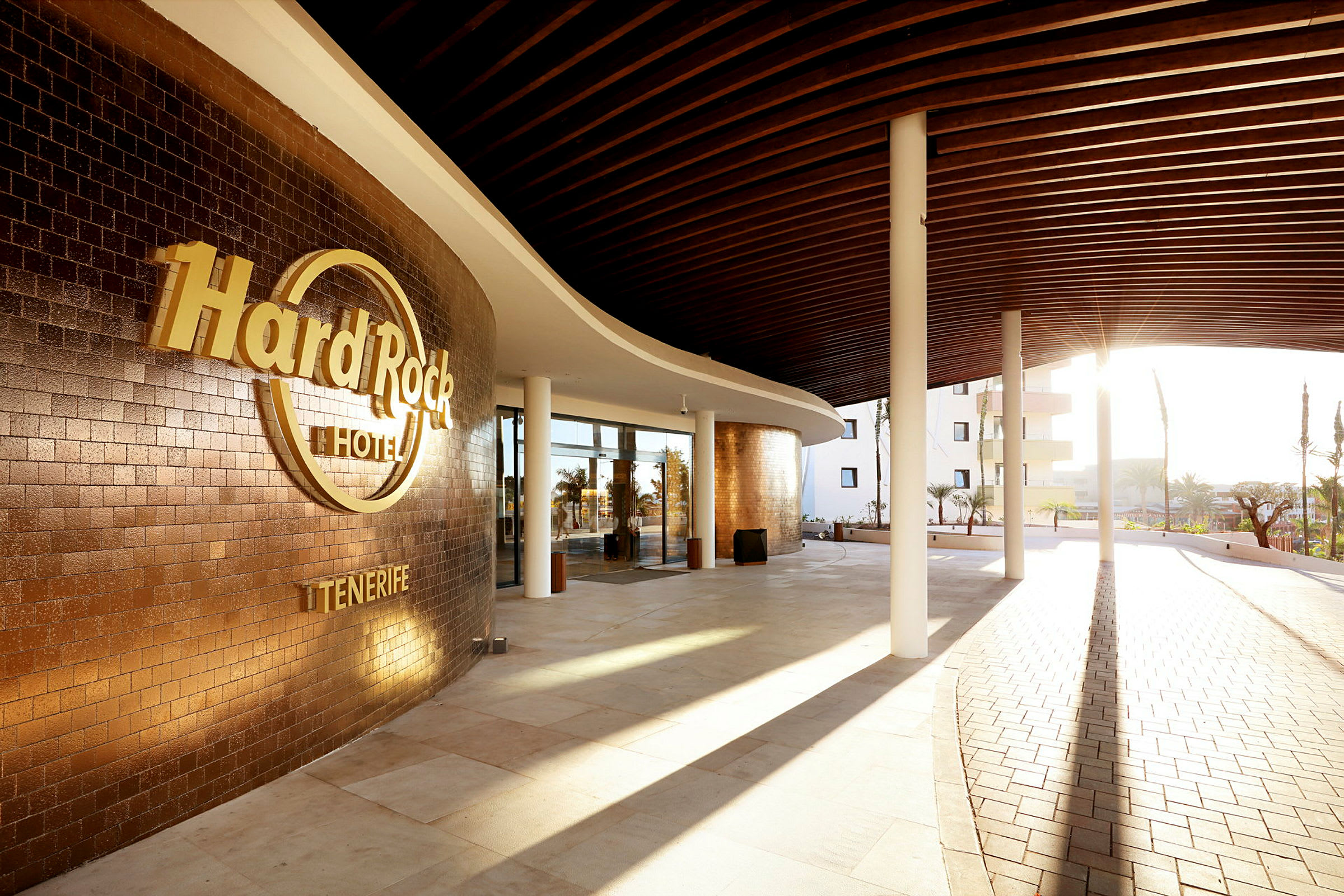 Ingången till Hard Rock Hotel Tenerife med solsken och modern design. (AI-genererad text)