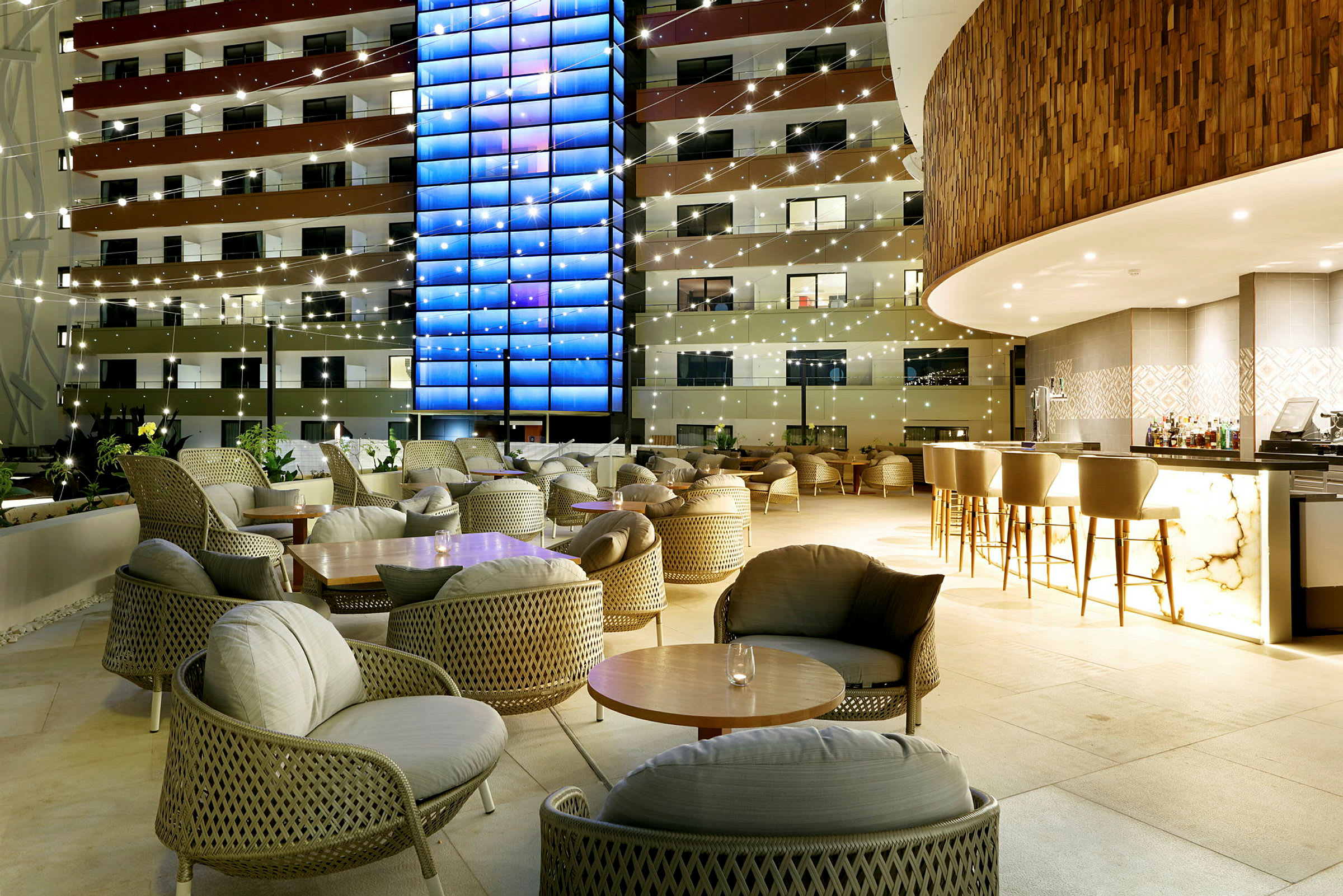 En upplyst hotellbar och sittgrupper på en terrass under kvällen. (AI-genererad text)