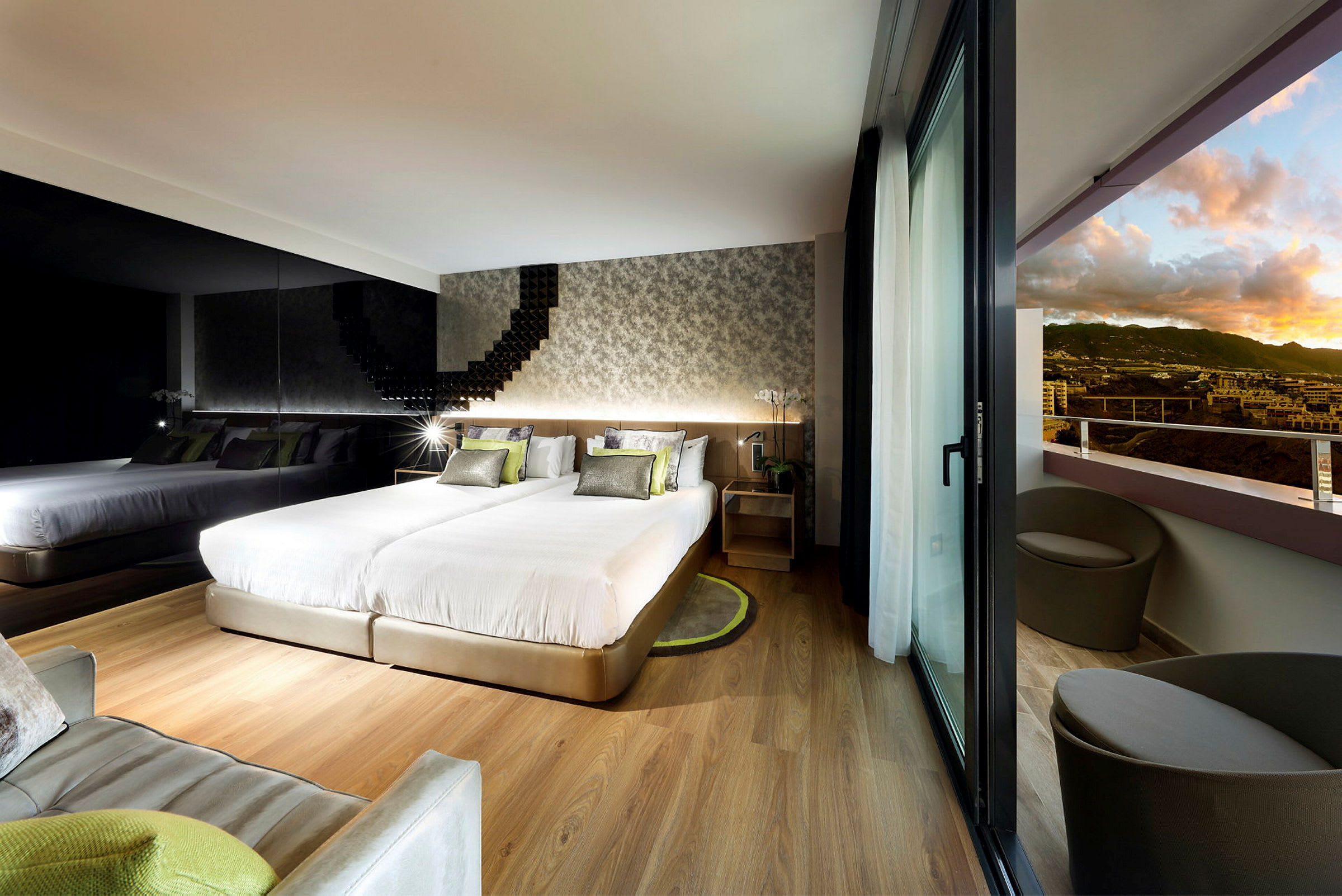Modernt hotellrum med två sängar, en spegelvägg och balkong med utsikt över landskapet. (AI-genererad text)