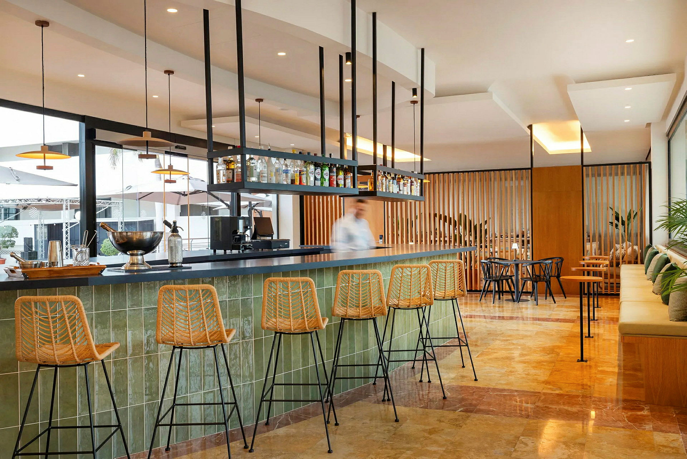 En modern bar med höga stolar och flaskor på hyllan över bardisken. (AI-genererad text)