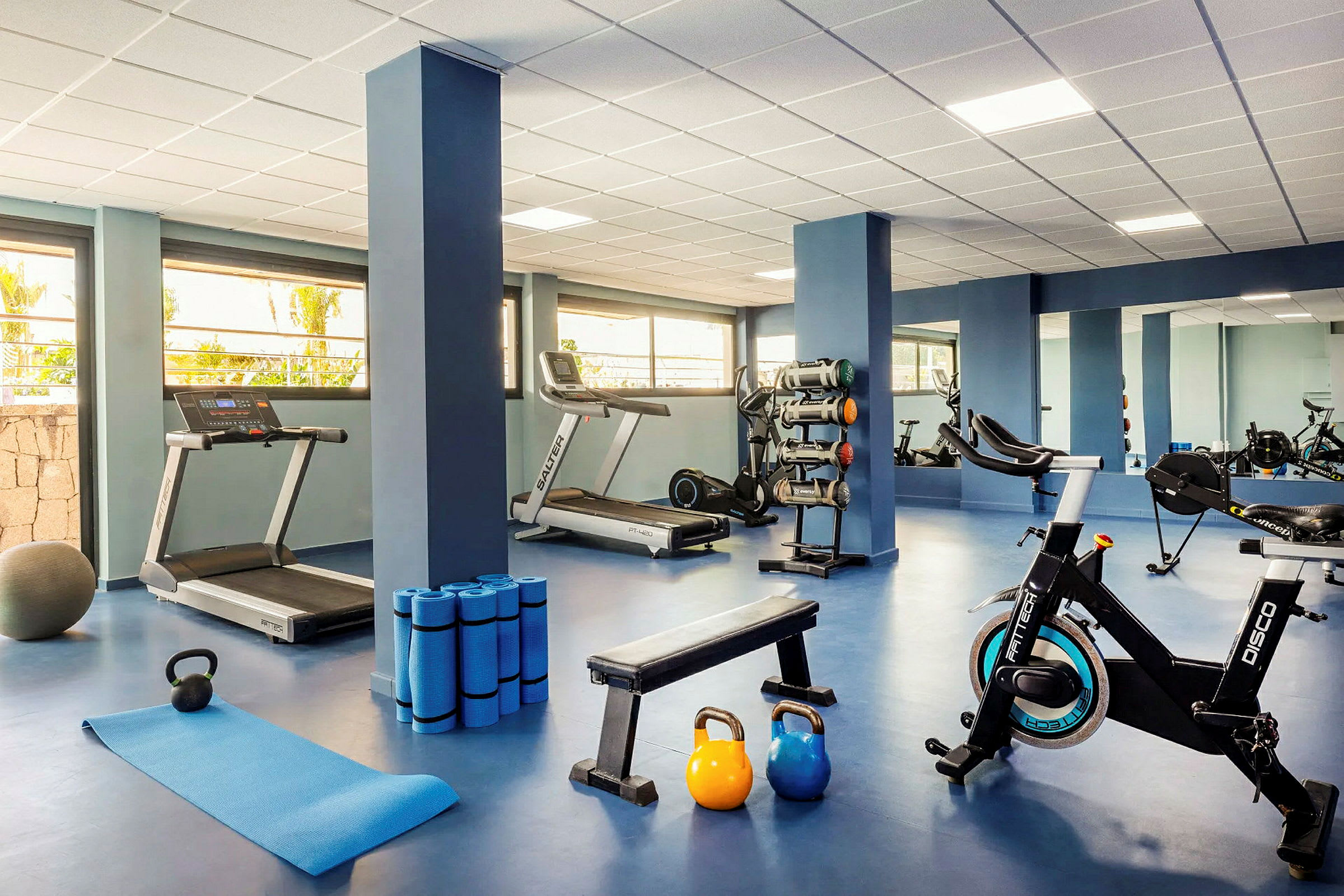 Ett gym med träningsutrustning som löpband, cykel, hantlar och fitnessmattor. (AI-genererad text)