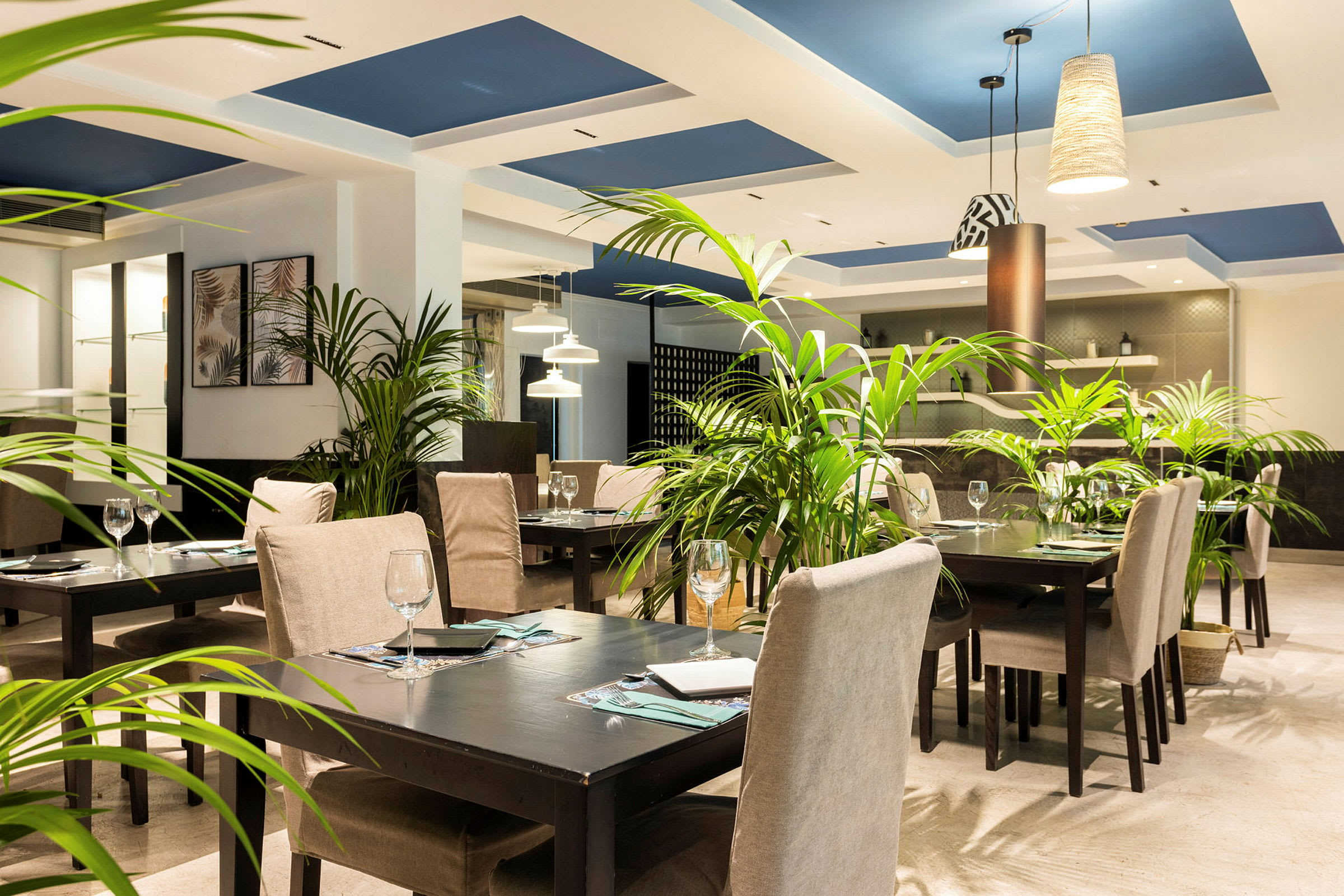 En restaurang med dukade bord, gröna växter och modern belysning. (AI-genererad text)