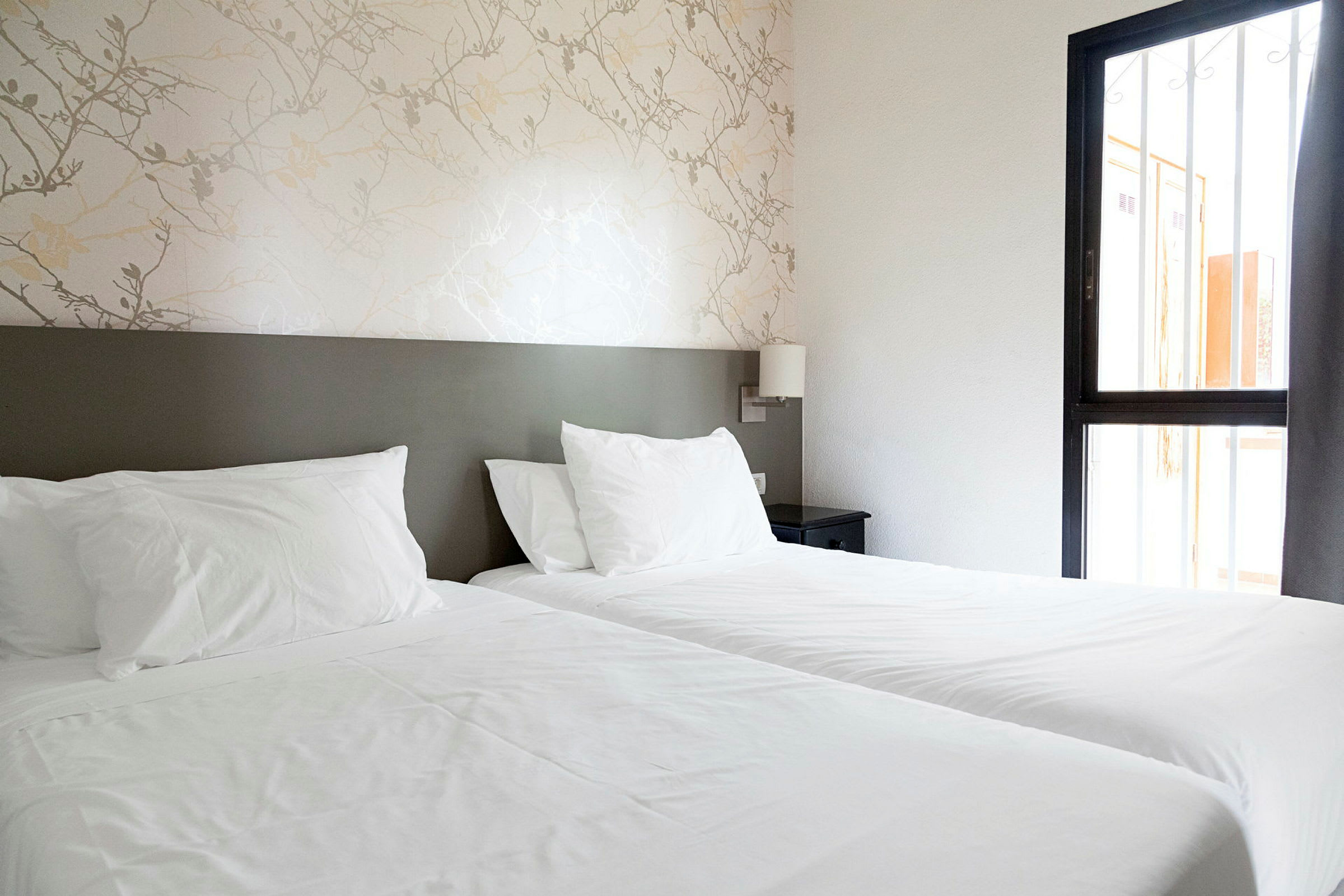 Ett hotellrum med två enkelsängar och ett nattduksbord.  (AI-genererad text)