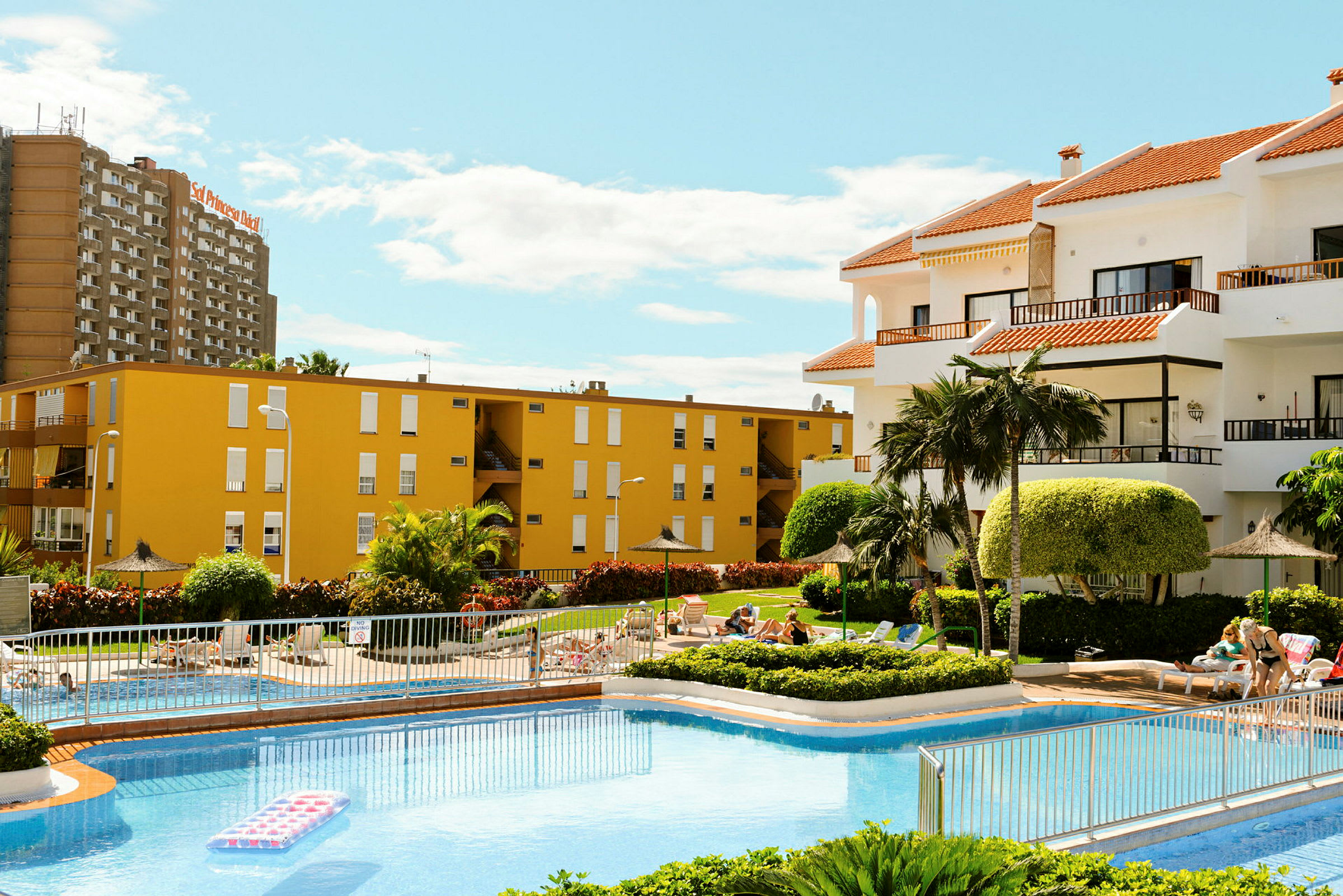 Uteområde med pool, liggstolar och omgivande byggnader. (AI-genererad text)
