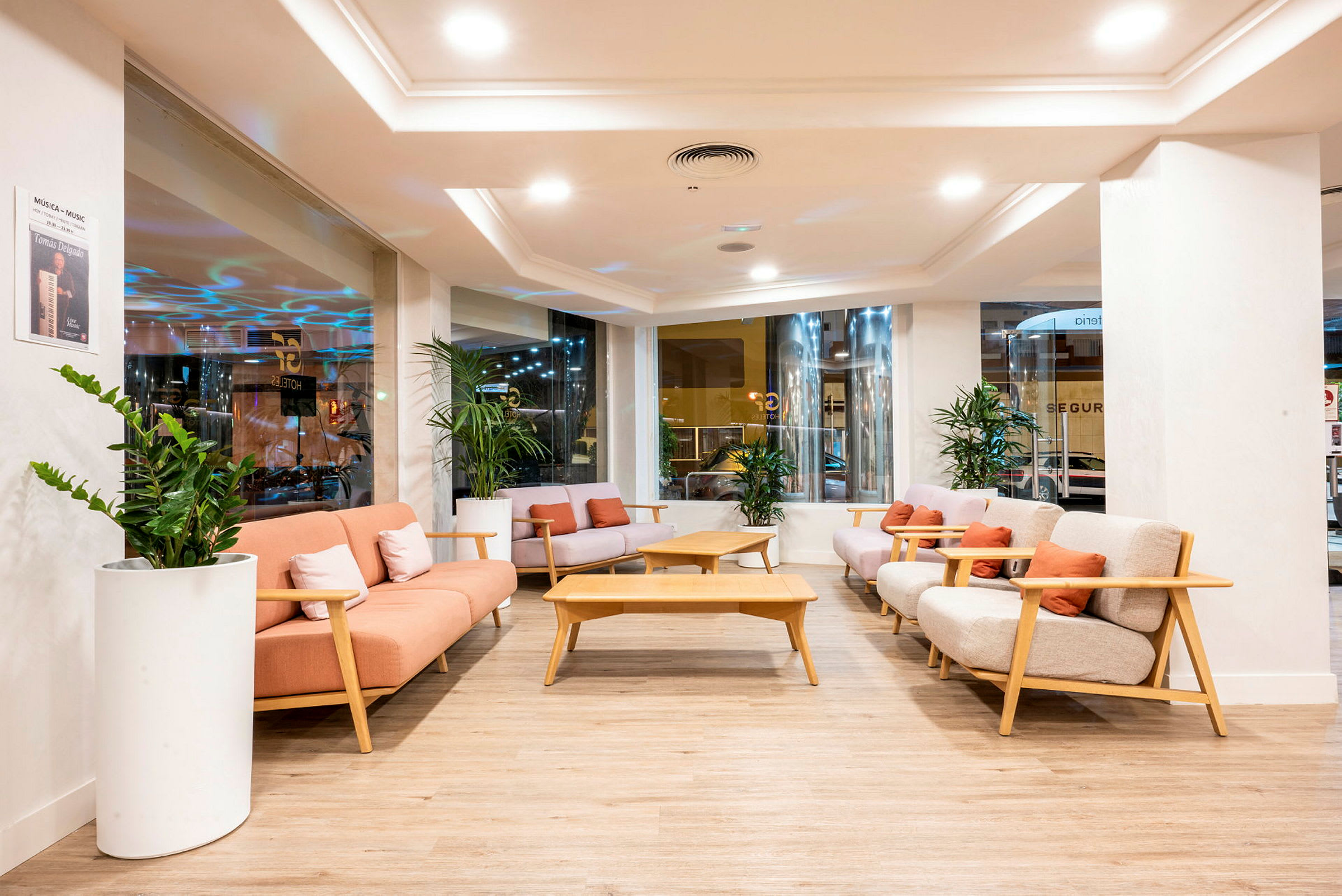 En hotelllobby med bekväma soffor, soffbord och gröna växter. (AI-genererad text)