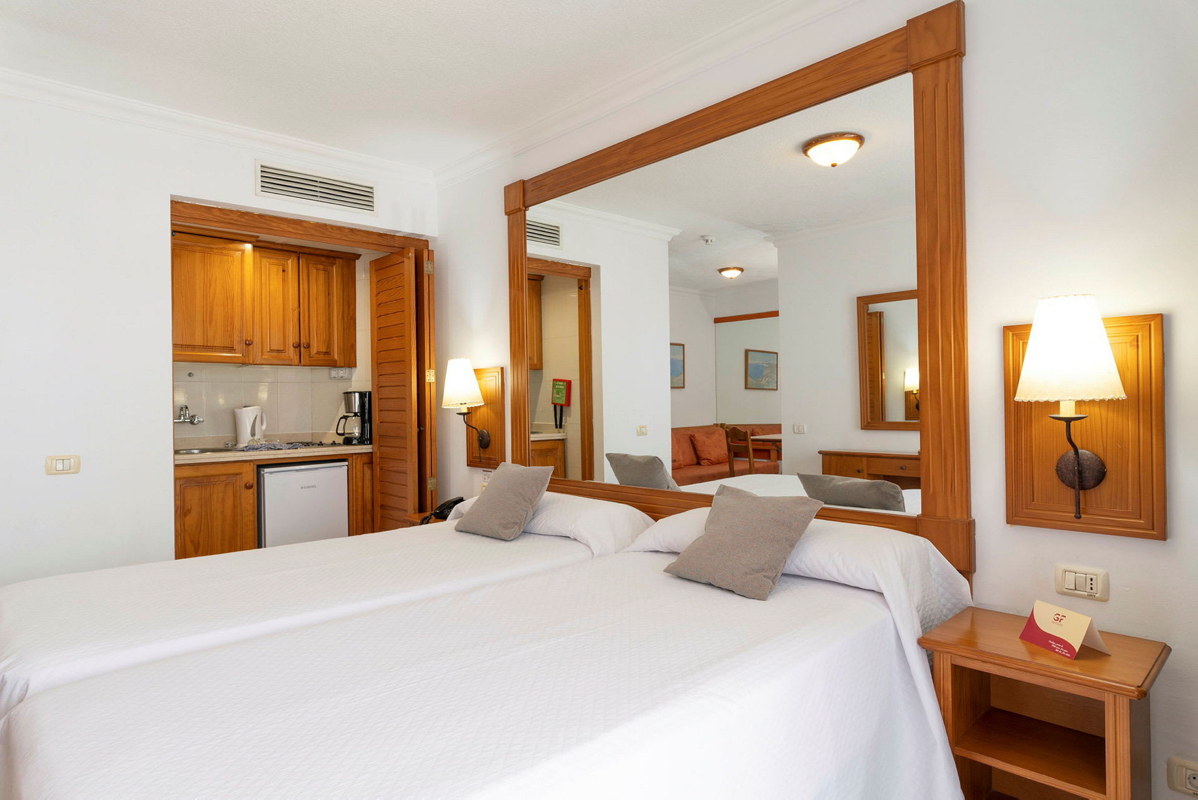 Hotellrum med två enkelsängar och en spegel. (AI-genererad text)