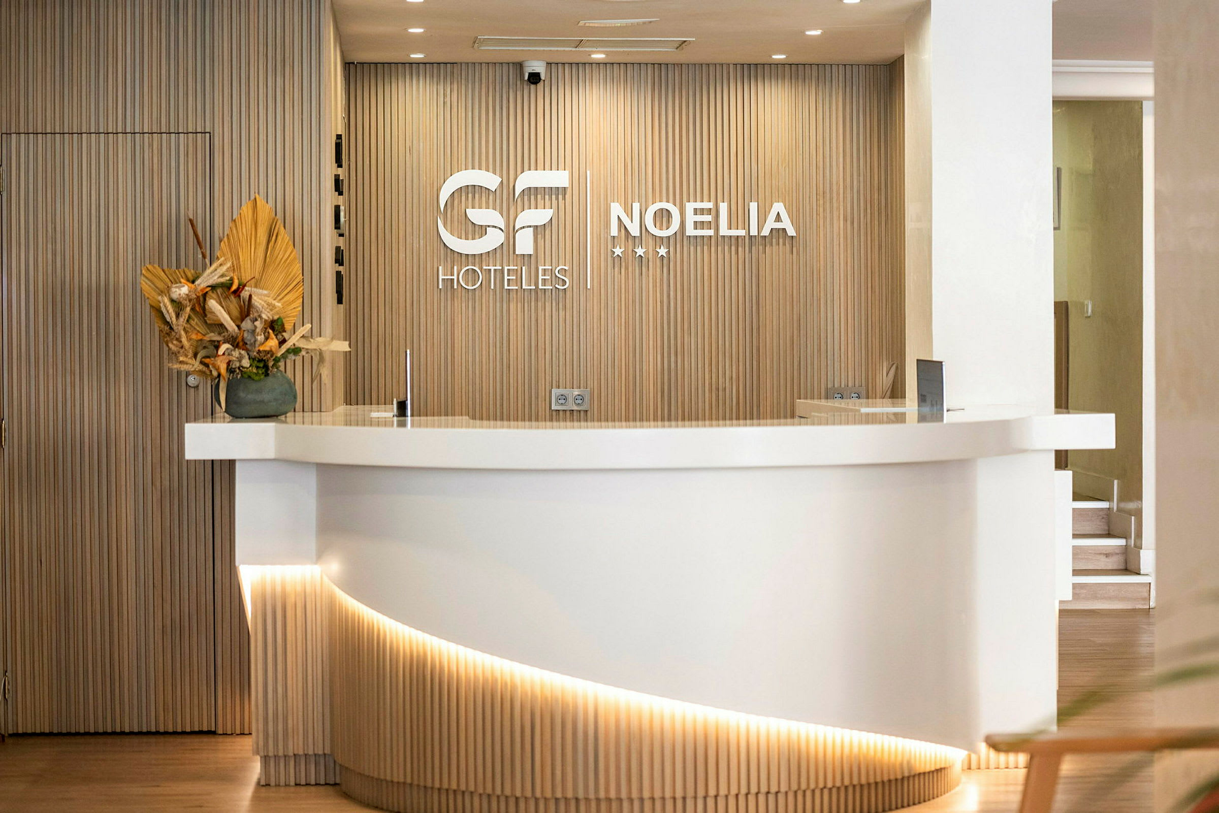 Hotellreception med en vit disk och en trävägg med logotyper. (AI-genererad text)