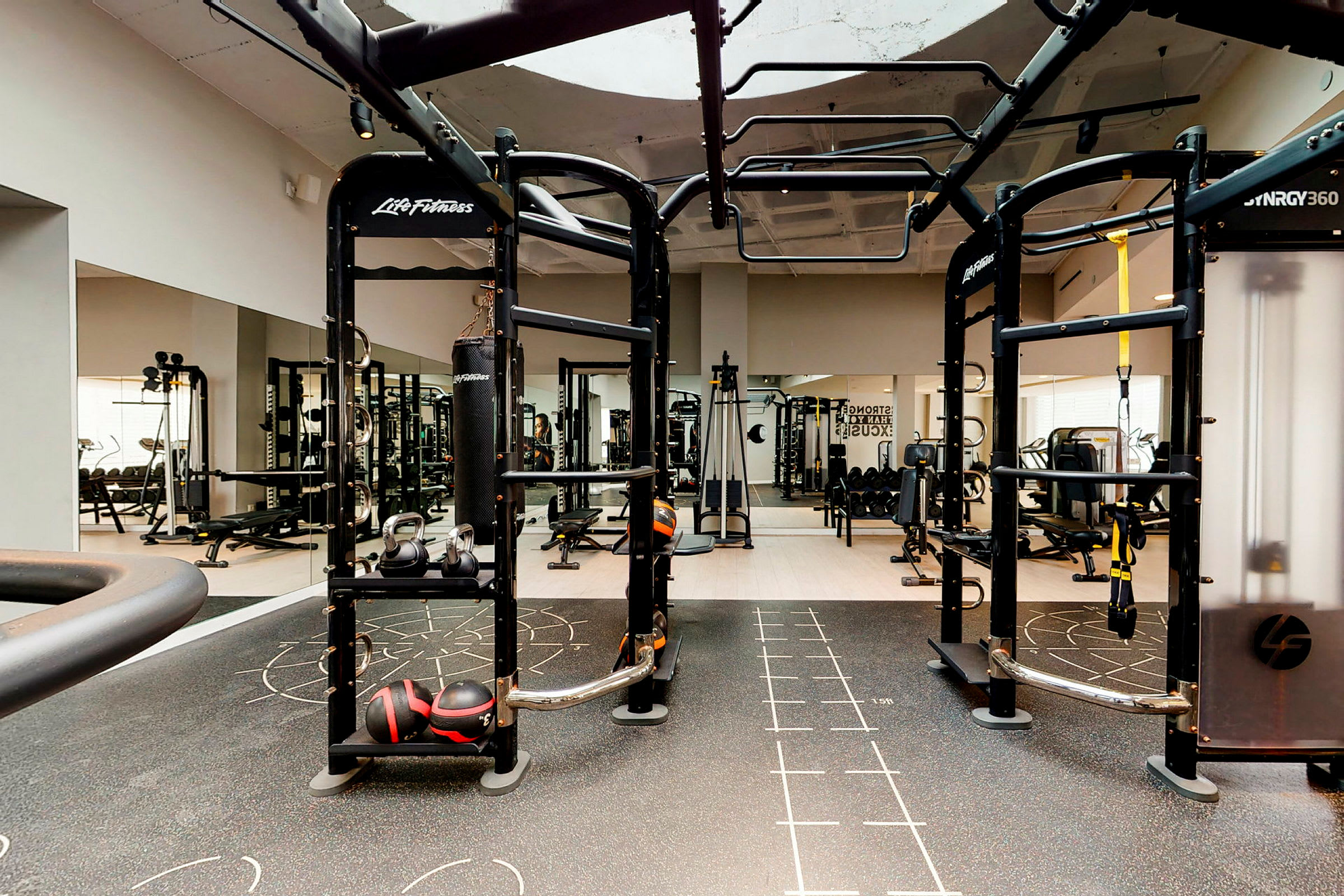 Ett gym med olika träningsredskap som kettlebells, boxsäck och styrketräningsmaskiner. (AI-genererad text)