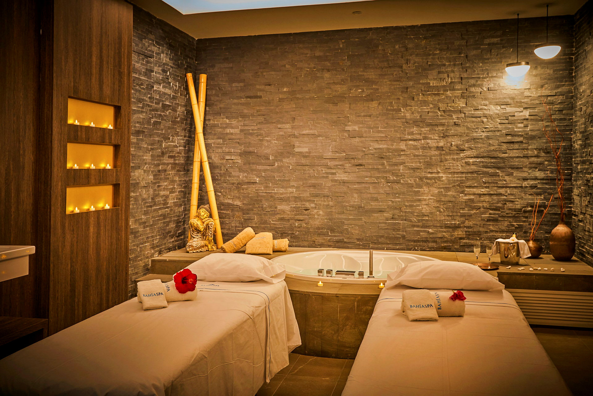 Ett spa-rum med två massagebänkar, en jacuzzi och dekorativa föremål. (AI-genererad text)