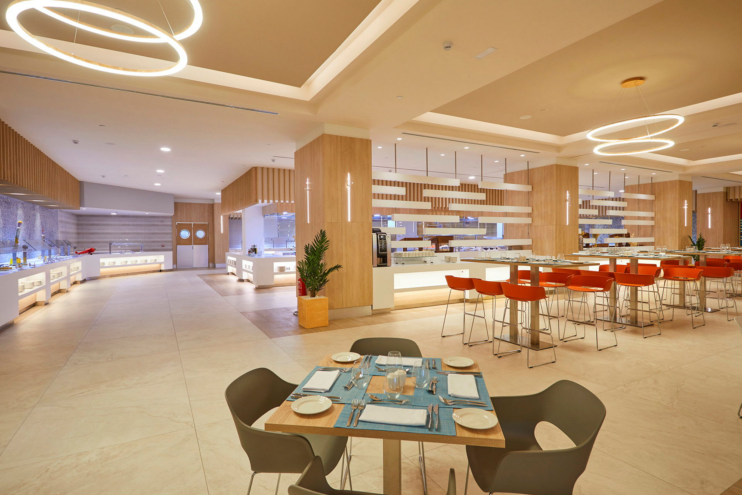 En modern restaurang med ljust inredning och möbler, bord med dukar och stolar, samt serveringsområden. (AI-genererad text)