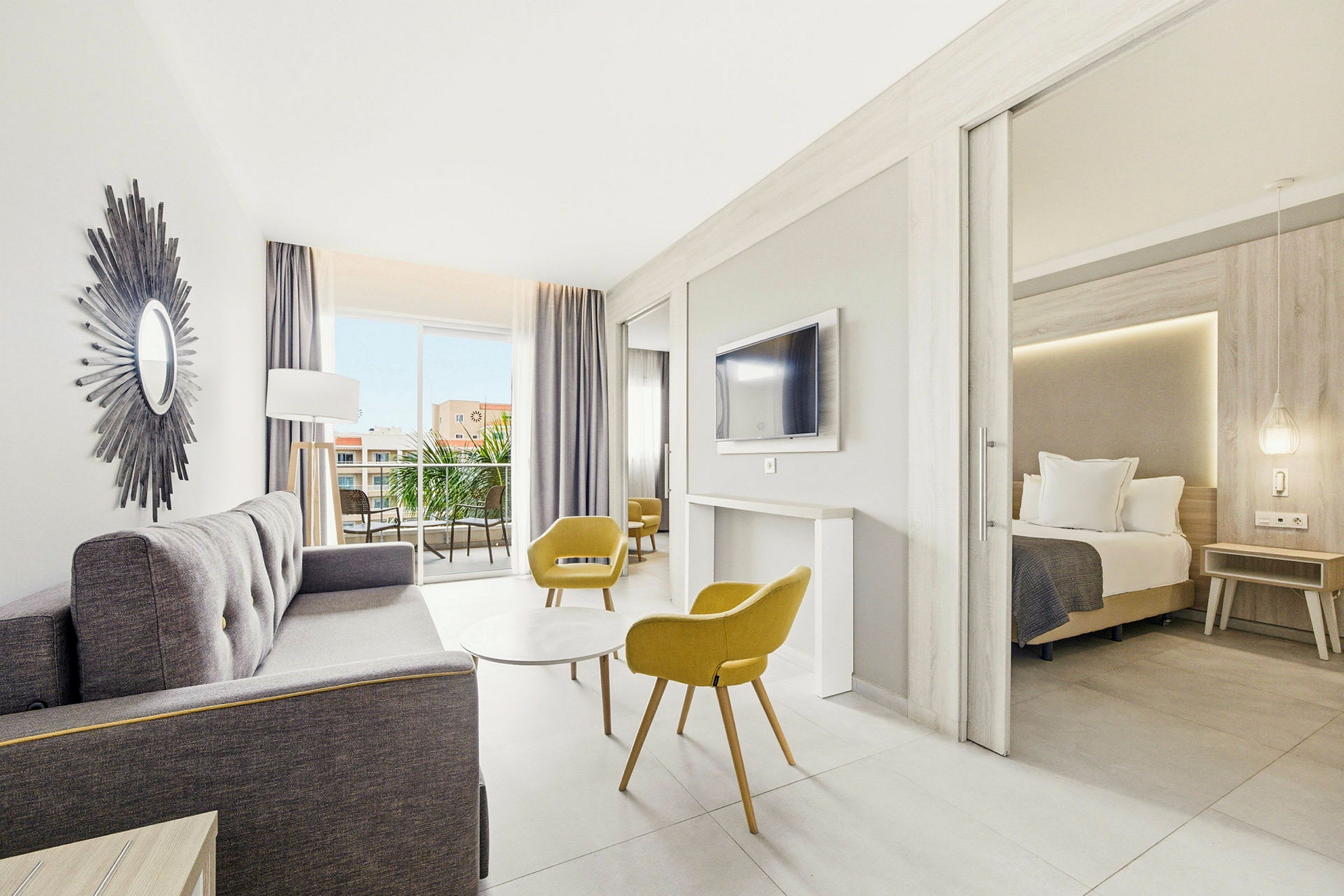 Ljust och modernt hotellrum med sittgrupp, sovrum och balkong. (AI-genererad text)