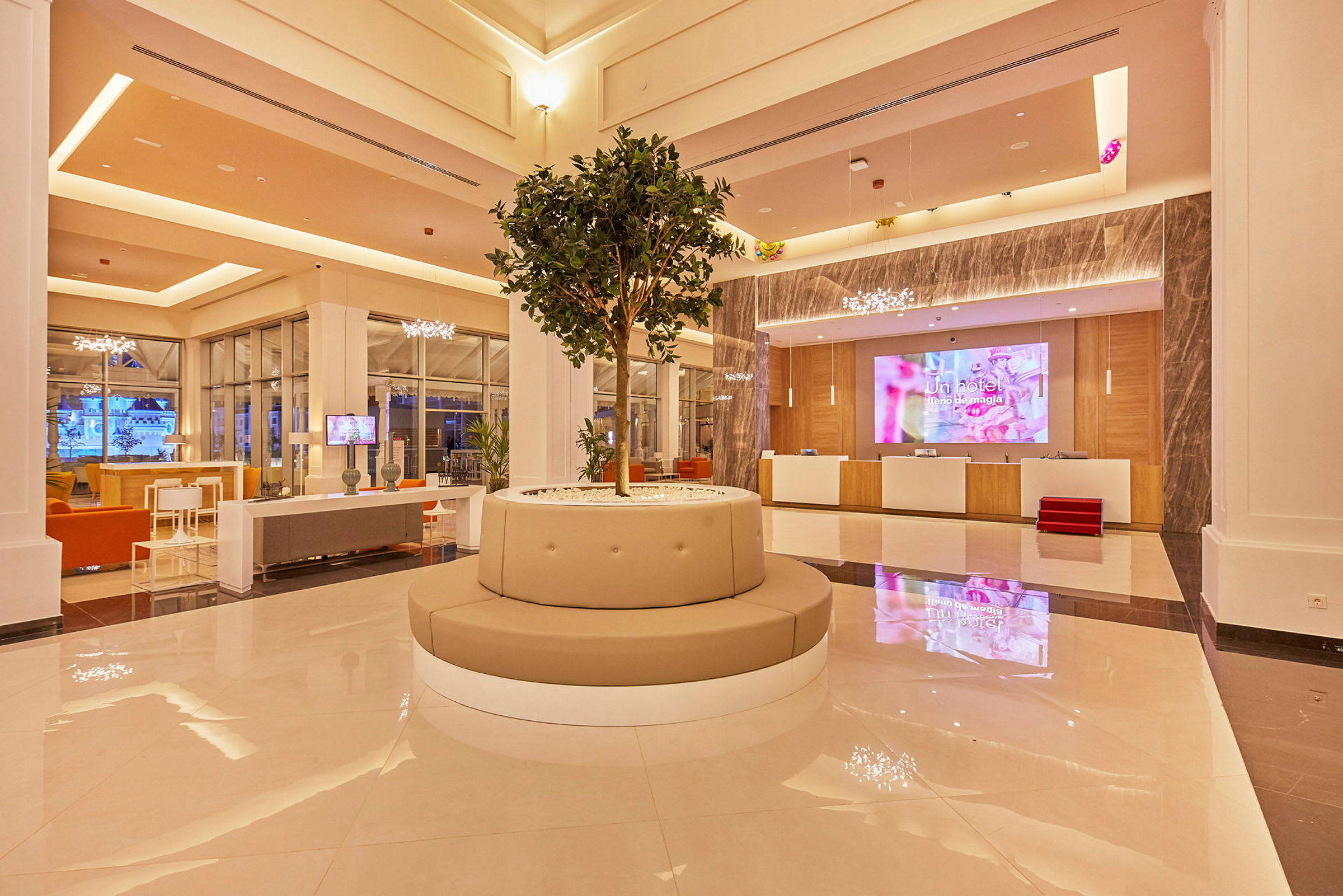 Hotellobby med centralt placerad sittmöbel och träd. (AI-genererad text)
