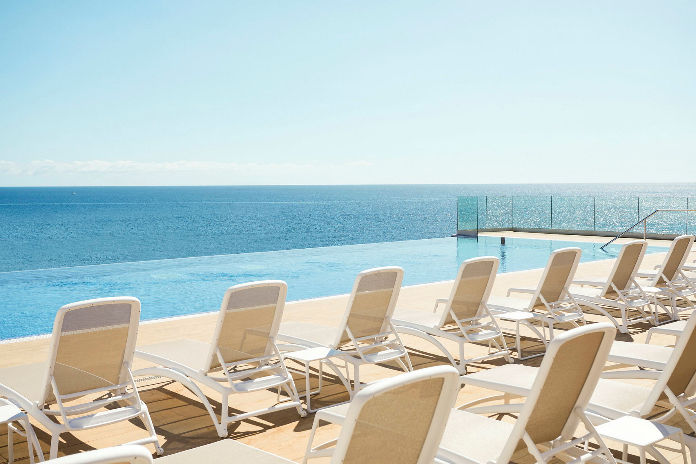 Solstolar vid en infinitypool med havsutsikt. (AI-genererad text)
