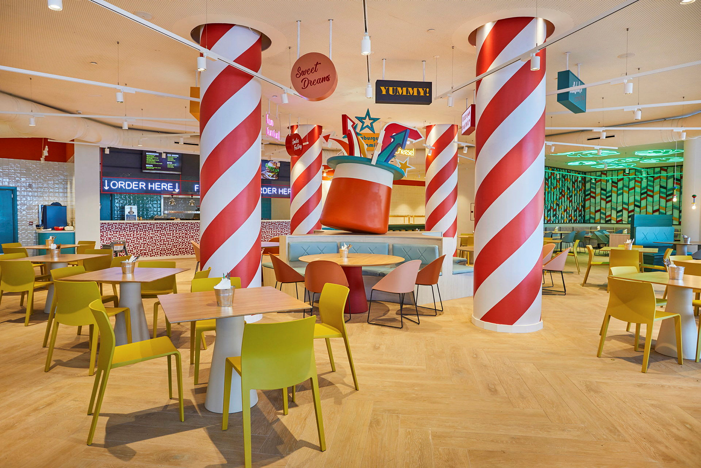 Restaurang med färgglad inredning, bord och stolar samt dekorativa stolpar. (AI-genererad text)