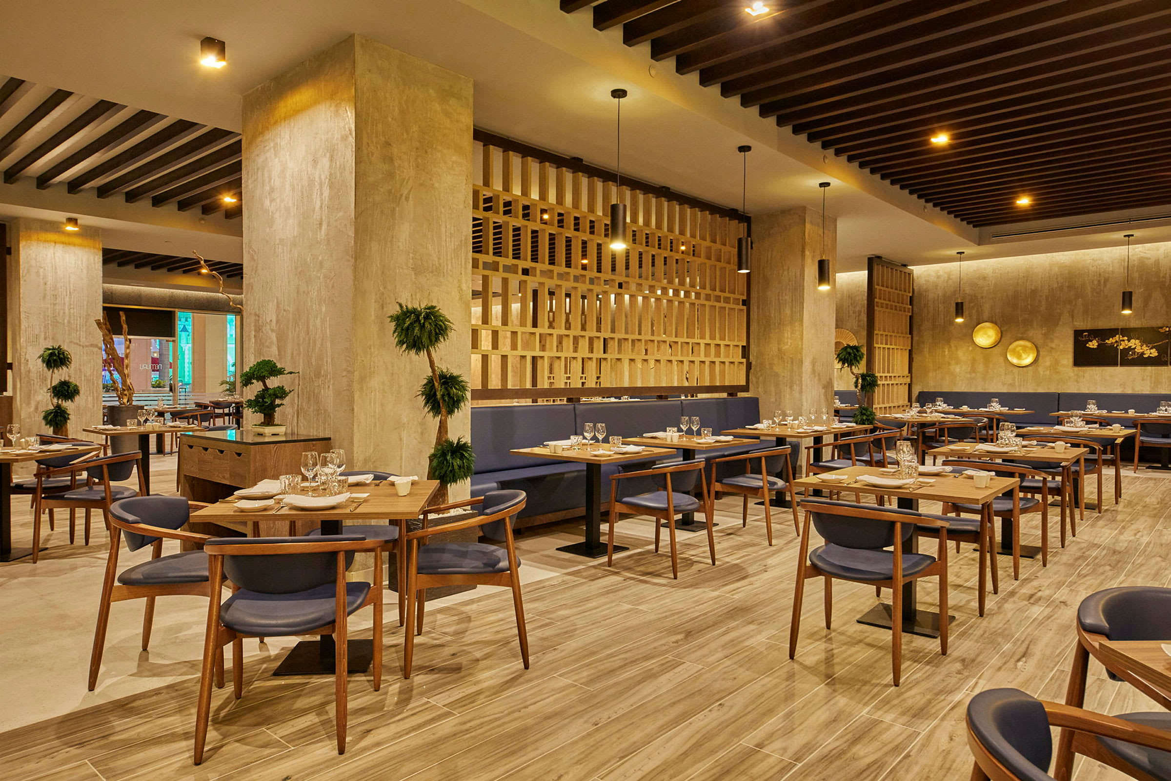 En modern restaurang med träinredning, bord med dukning och blå stolar. (AI-genererad text)