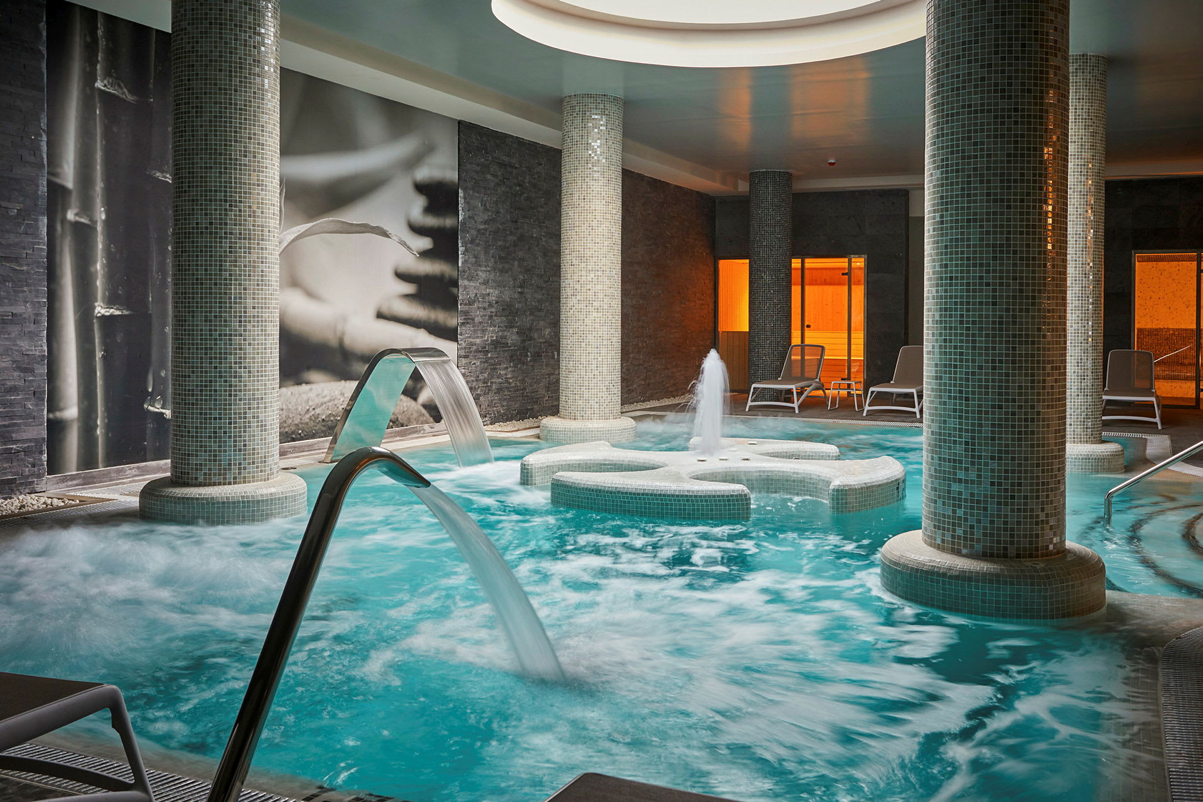 Inomhusspa med pool, vattenjets och loungestolar. (AI-genererad text)
