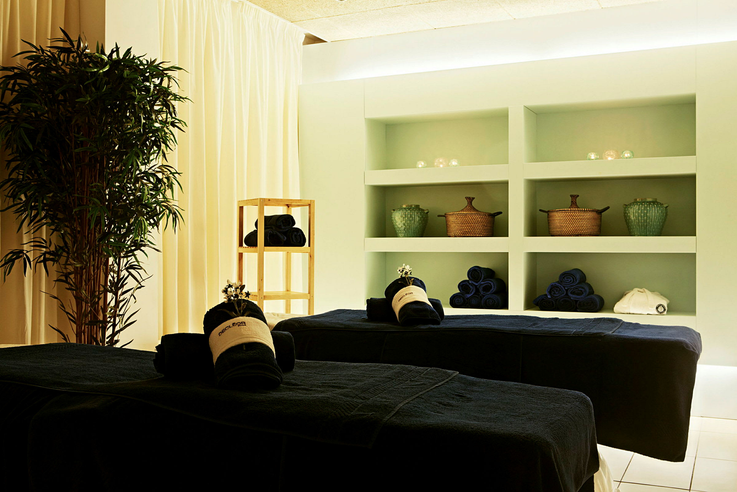 Ett spa-rum med massagebänkar, handdukar och dekorationer. (AI-genererad text)