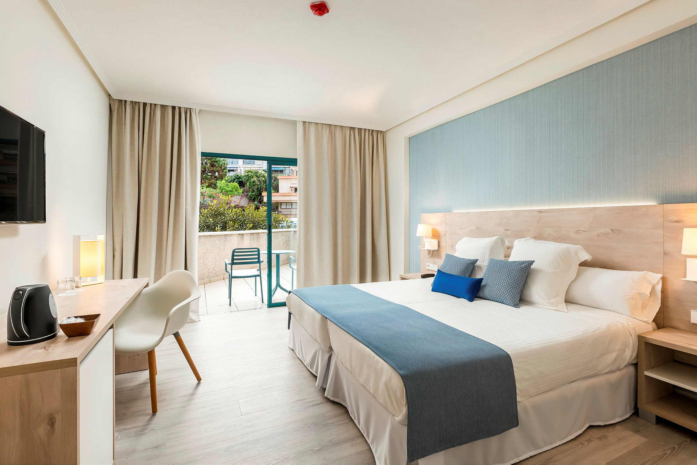 Ett modernt hotellrum med en stor säng och öppet till en balkong. (AI-genererad text)