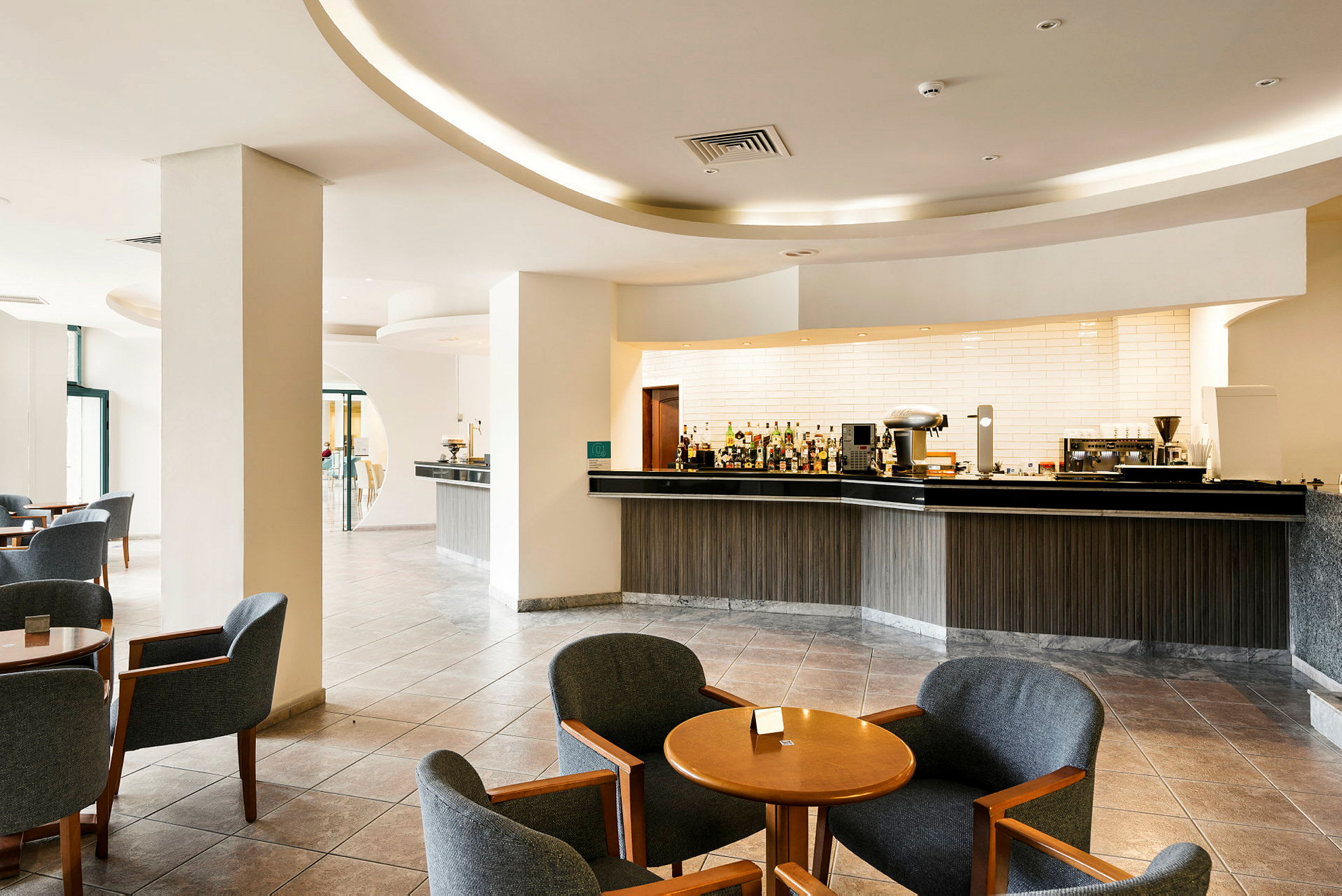 En modern hotellbar med bekväma sittplatser och en välutrustad barmiljö. (AI-genererad text)