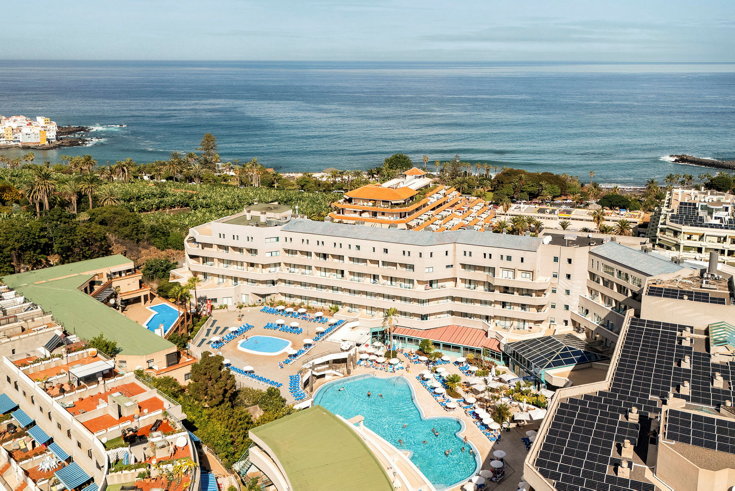 Vy över ett semesterhotell med poolområde nära havet. (AI-genererad text)