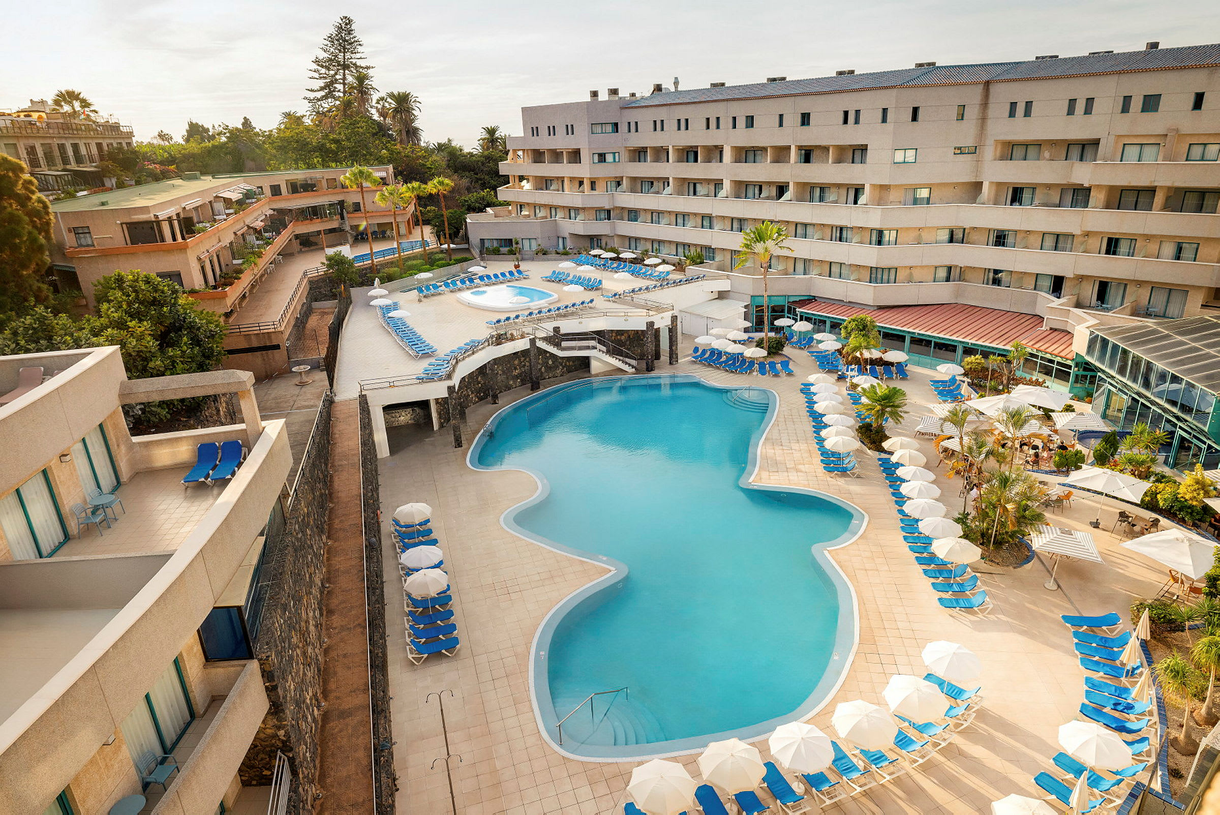 En hotellresort med en stora pool och solstolar runtomkring. (AI-genererad text)