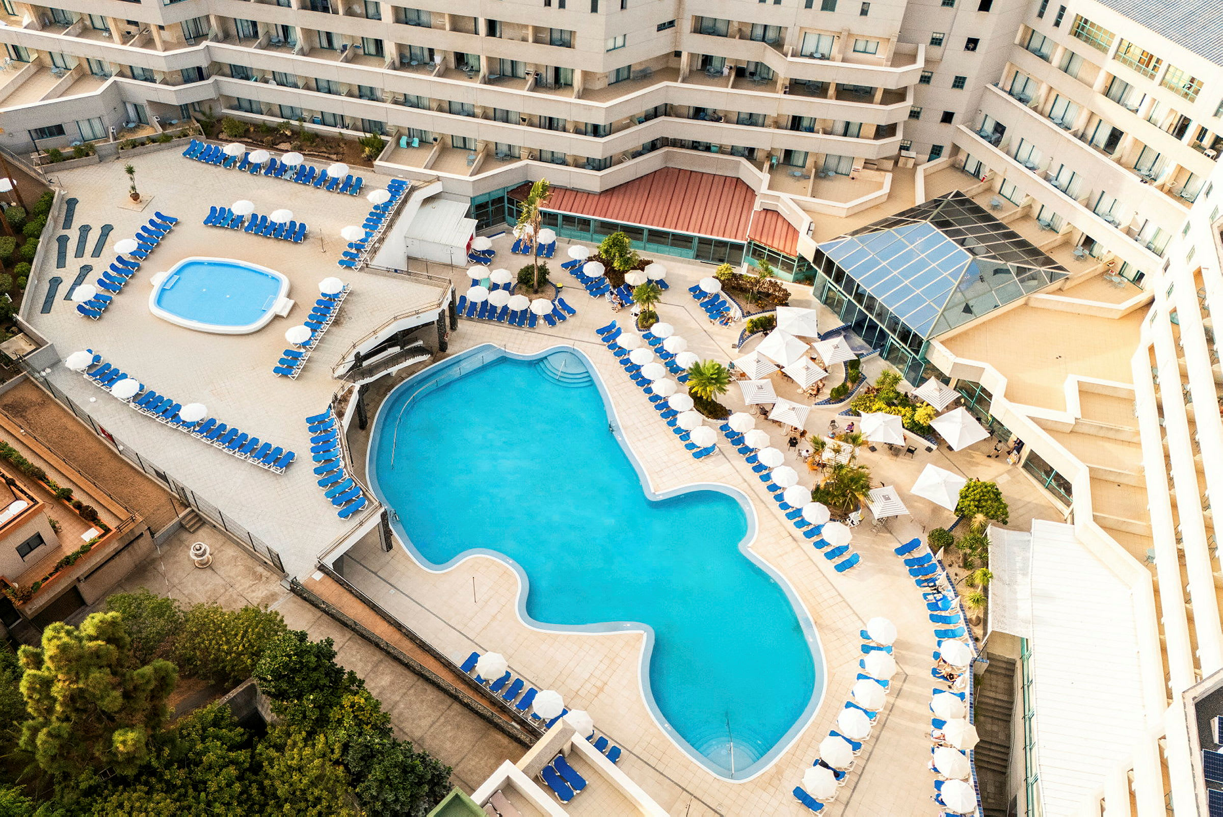 Flygfoto av hotellpoolområde med solstolar och parasoller. (AI-genererad text)
