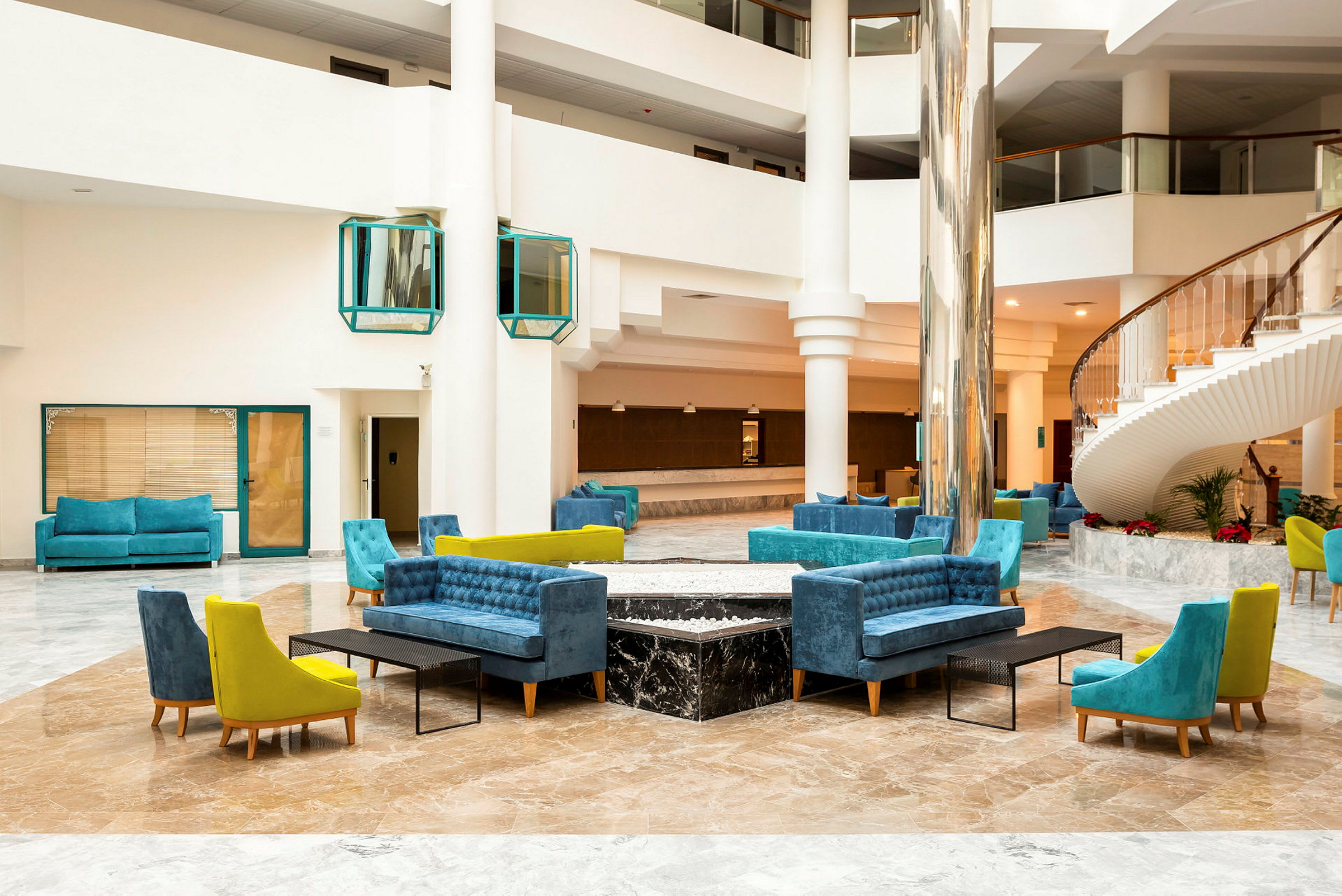 Interiör av en hotellobby med sittgrupper och en spiraltrappa. (AI-genererad text)