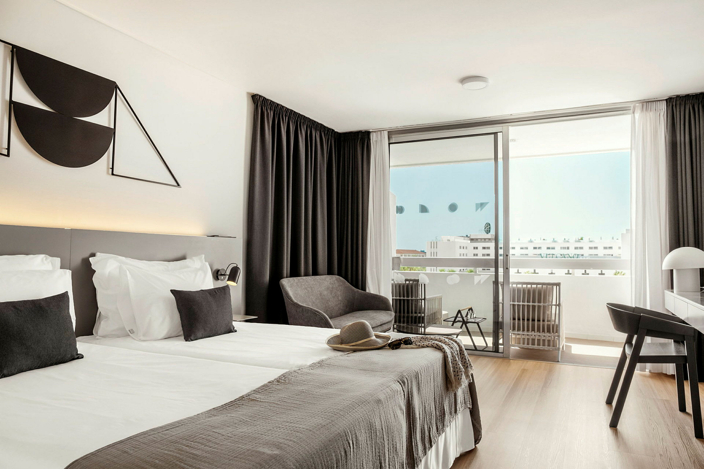 Ett modernt hotellrum med dubbelsäng, sittgrupp och balkong. (AI-genererad text)