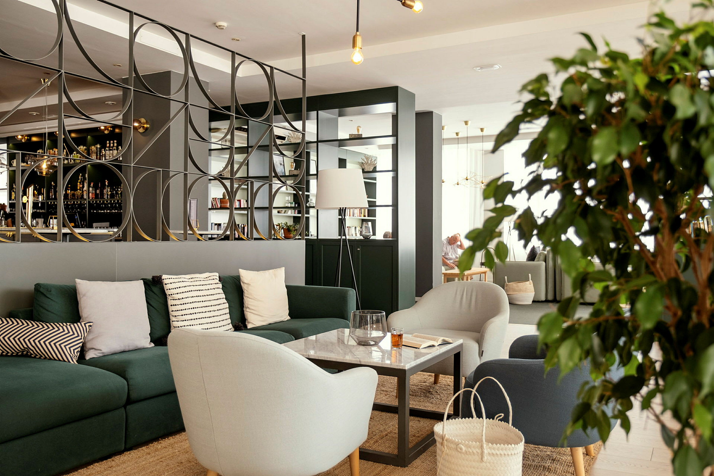 En modern lounge med soffor, fåtöljer och ett bord framför en dekorativ avskiljare. (AI-genererad text)