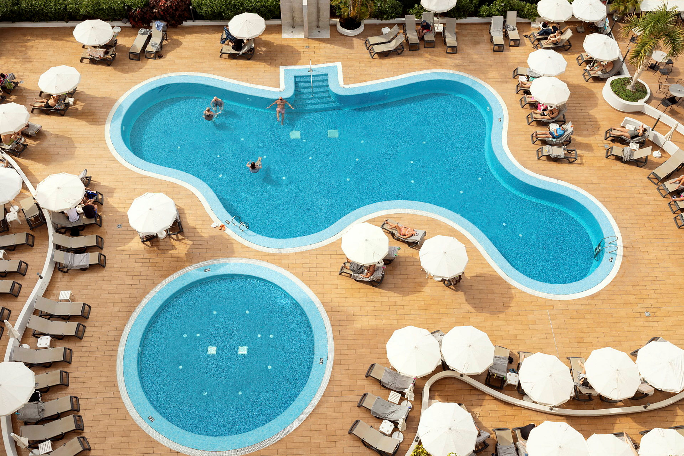 Flygbild på en pool med solsängar och parasoll. (AI-genererad text)
