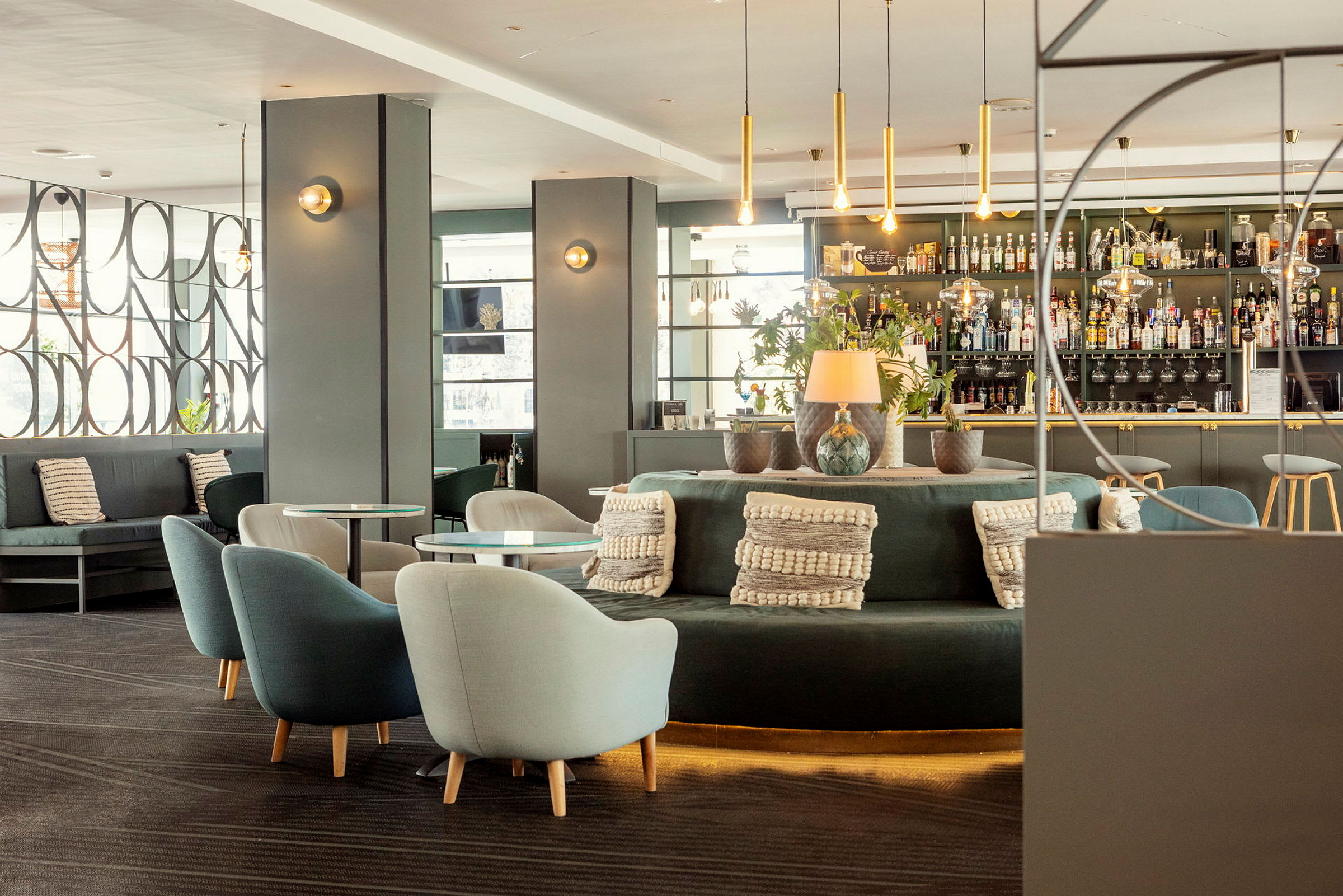 Modernt inredd hotellbar med sittgrupper, dekorationer och hyllor fyllda med flaskor. (AI-genererad text)