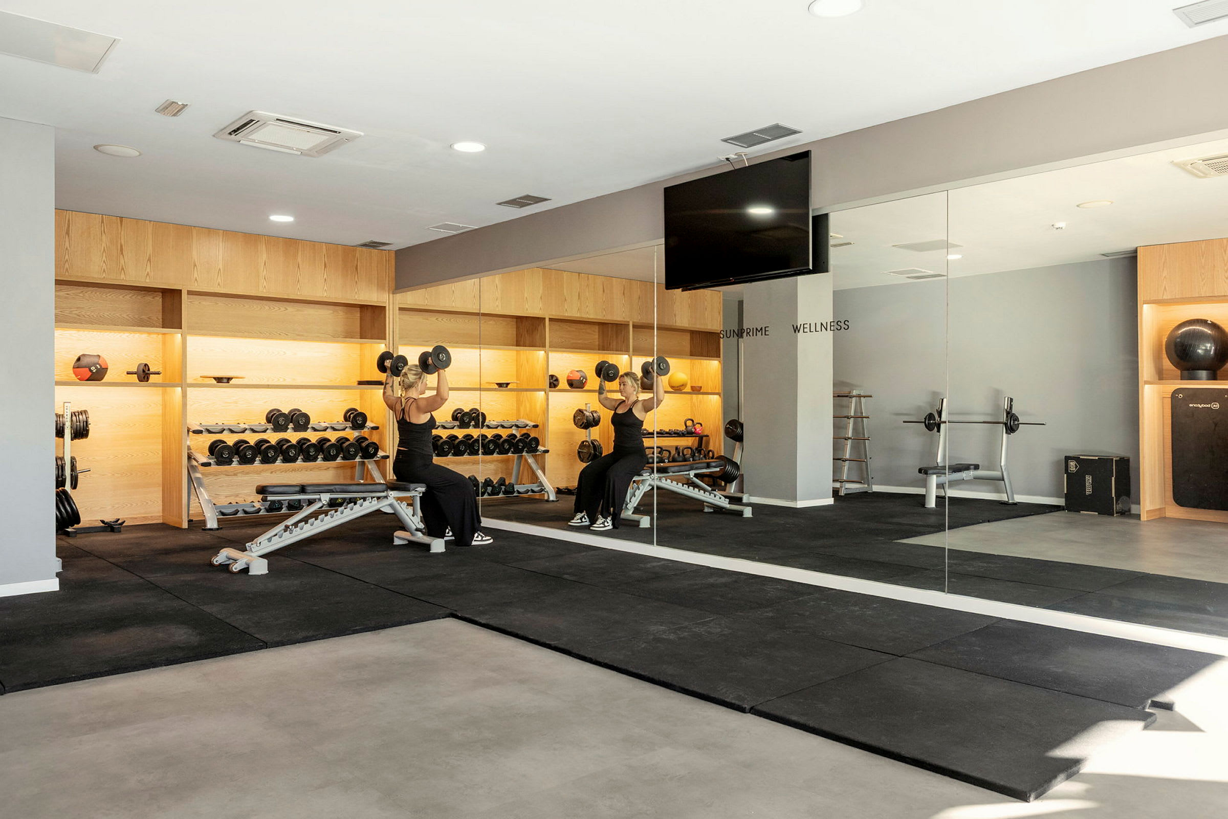 Ett gym med träningsutrustning såsom hantlar, spegelvägg och fitnessmaskiner. (AI-genererad text)