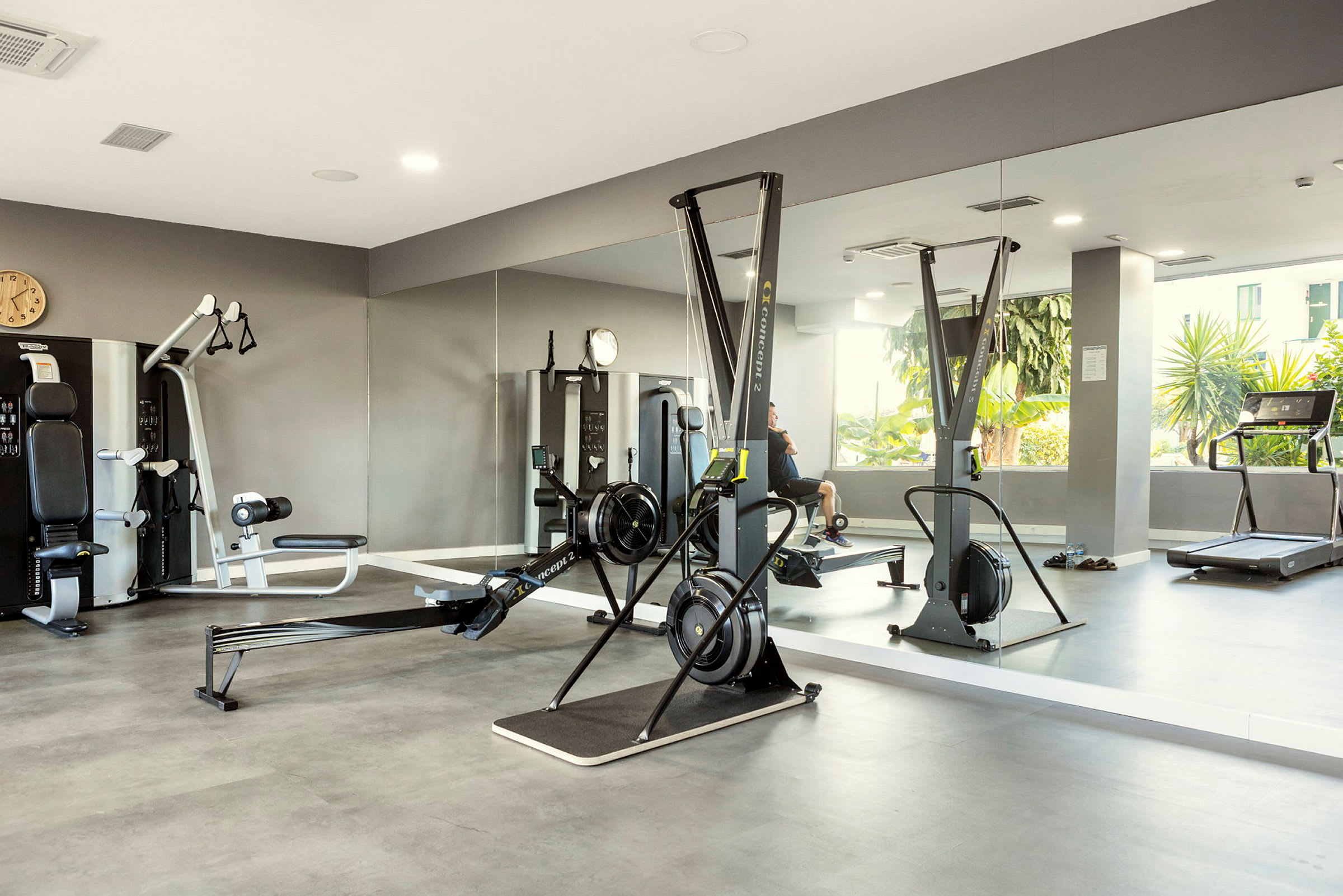 Ett gym med olika träningsmaskiner och spegelvägg. (AI-genererad text)