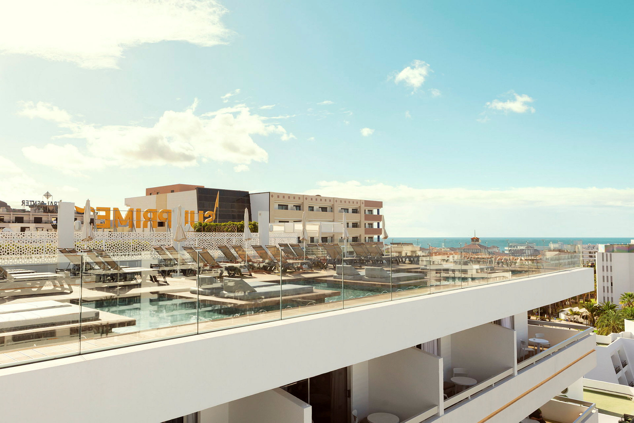 En takterrass med solstolar och en pool, med utsikt över en stad och havet. (AI-genererad text)