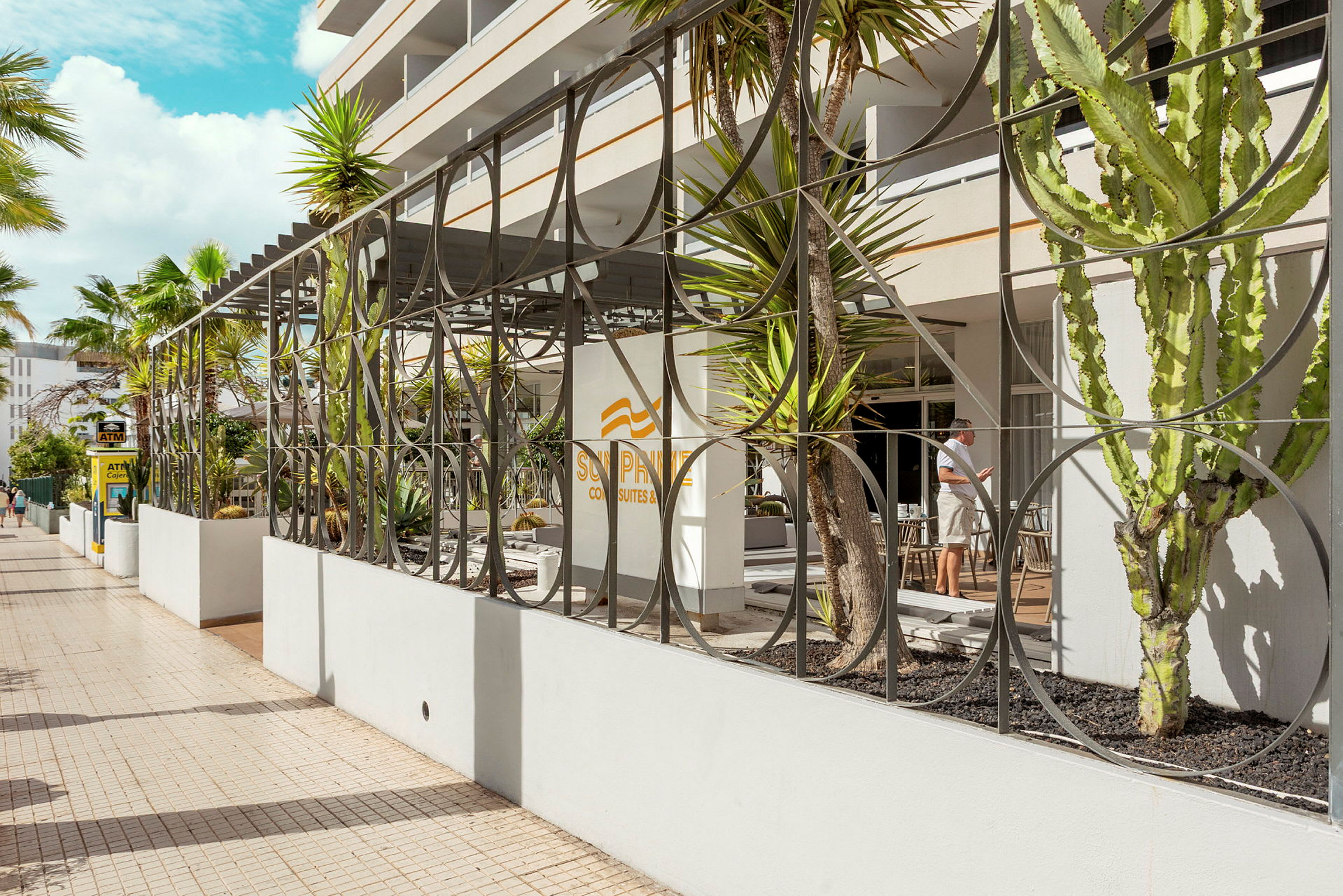 Hotellentré med dekorativt staket och växter. (AI-genererad text)
