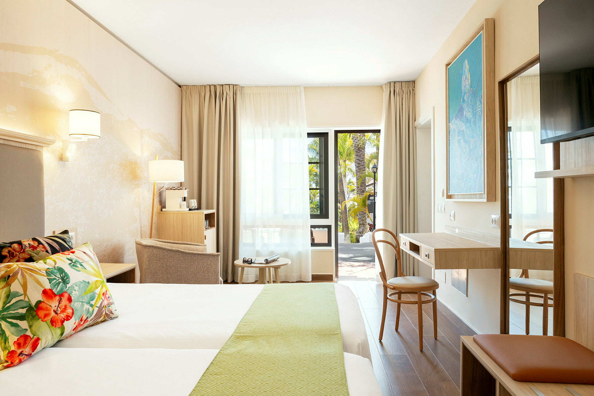 Bild av ett modernt hotellrum med dubbelsäng, skrivbord och sittmöbler, samt en öppen dörr mot en balkong. (AI-genererad text)