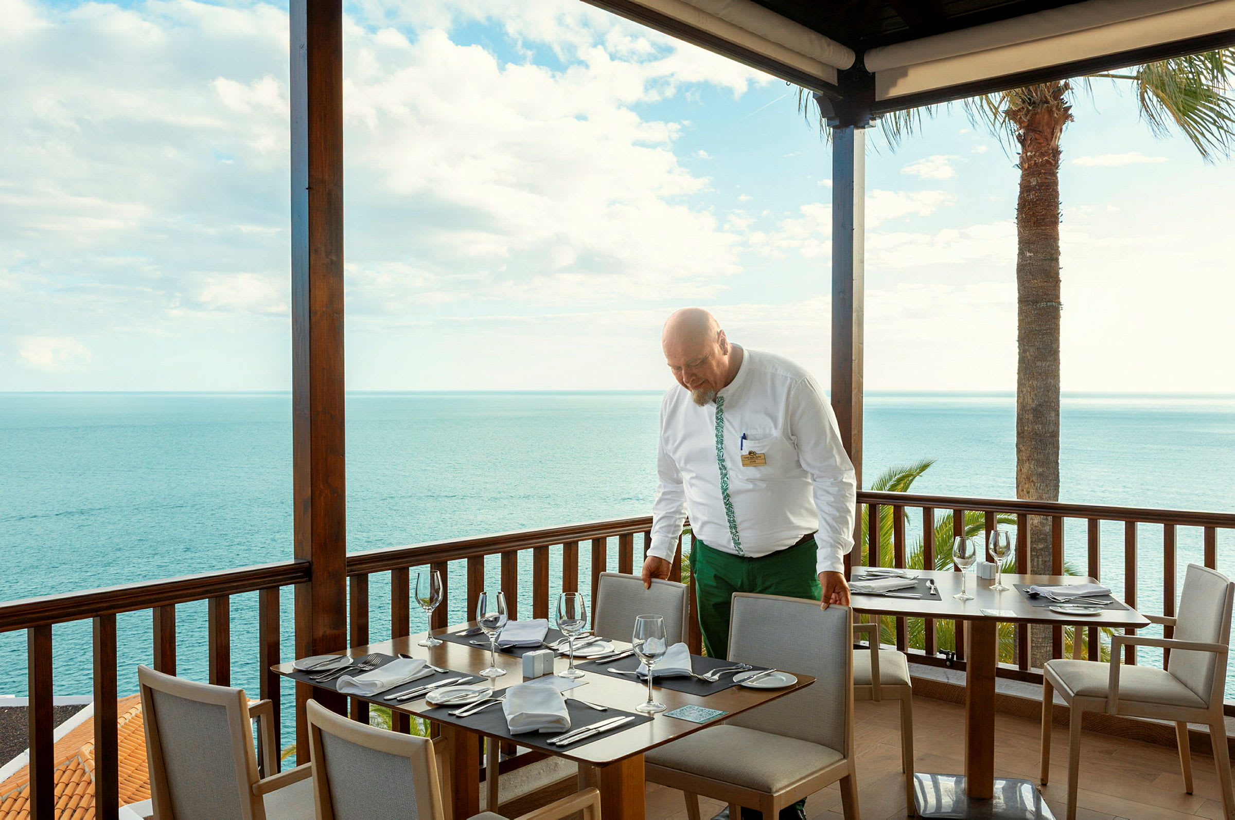 En matplats med dukade bord vid en terrass med utsikt över havet. (AI-genererad text)