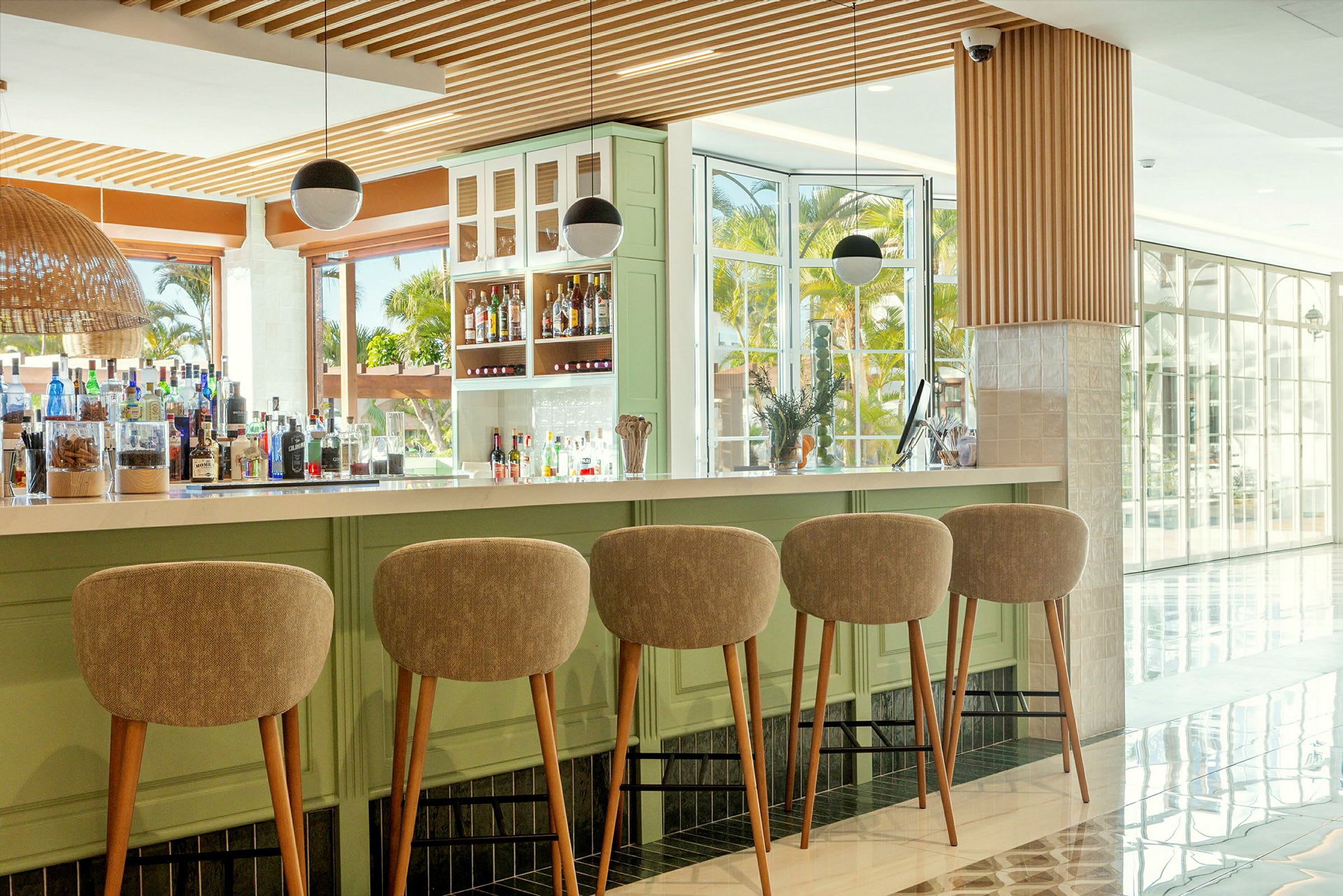 Fem barstolar står vid en modern bar med flaskor och glas på en ljus disk. (AI-genererad text)