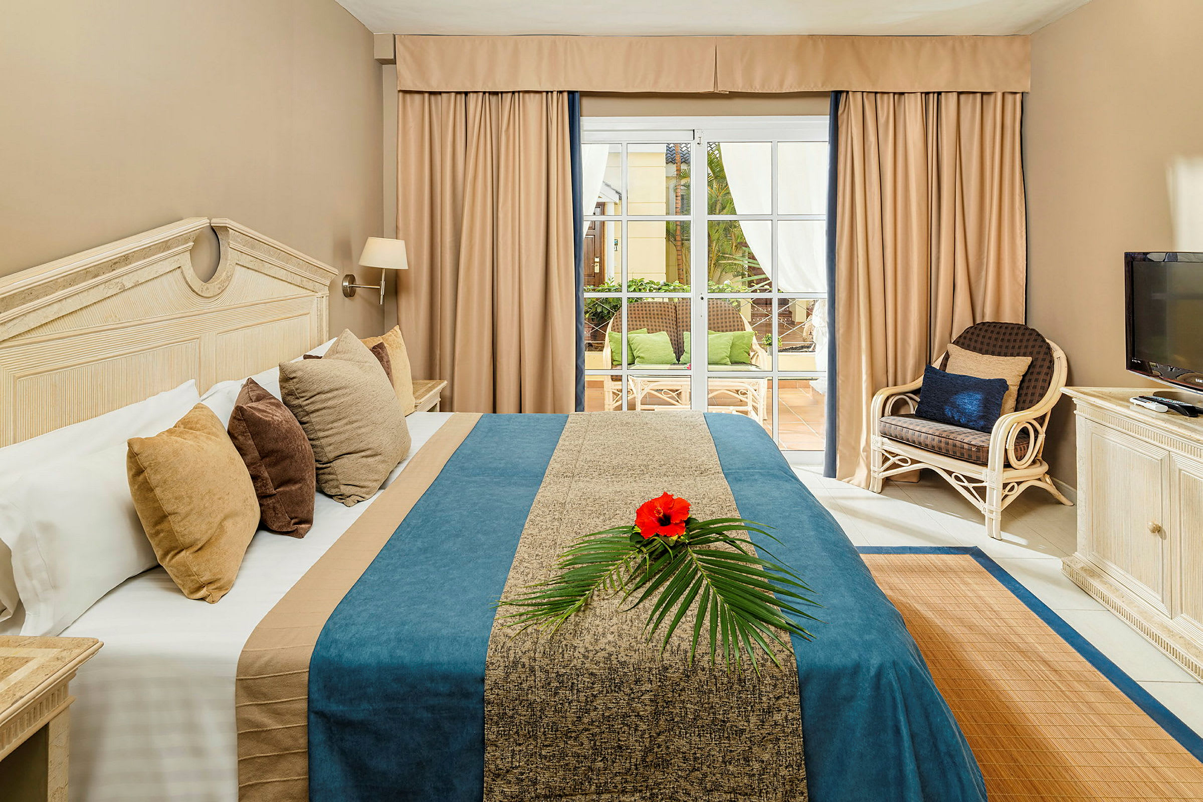 Bild av ett hotellrum med en säng, en TV, och utsikt mot en terrass. (AI-genererad text)