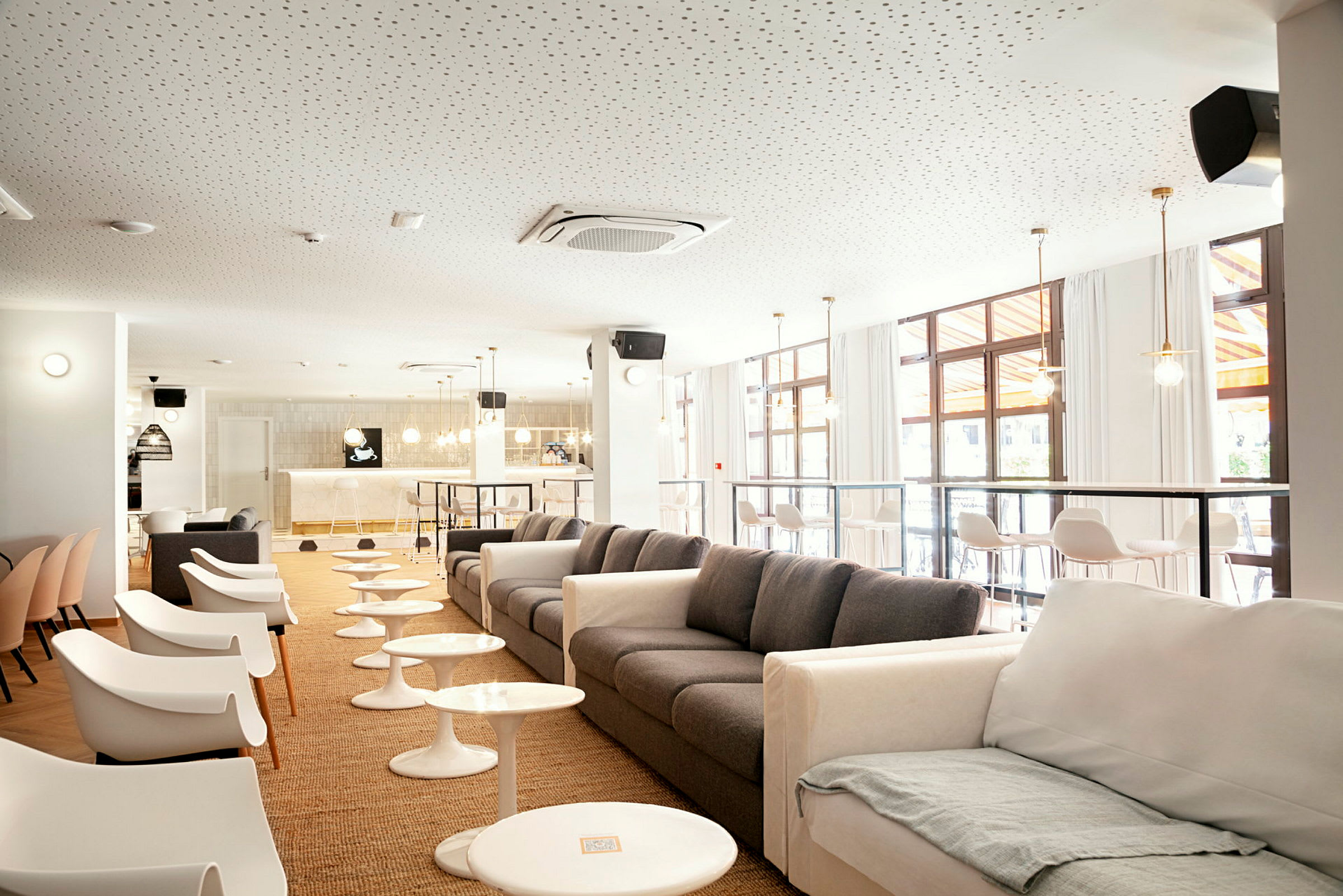 En modern lounge med soffor och stolar, små bord och en bar i bakgrunden. (AI-genererad text)