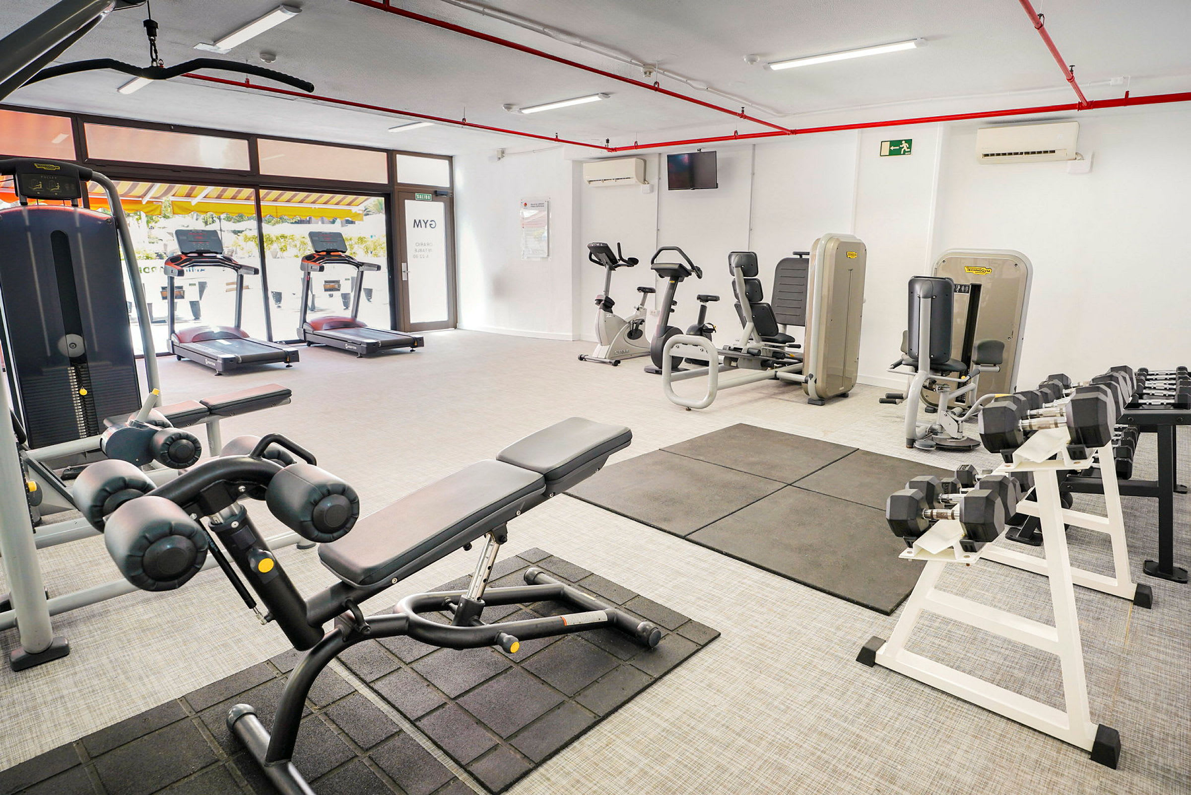Ett gym med olika träningsmaskiner och vikter. (AI-genererad text)