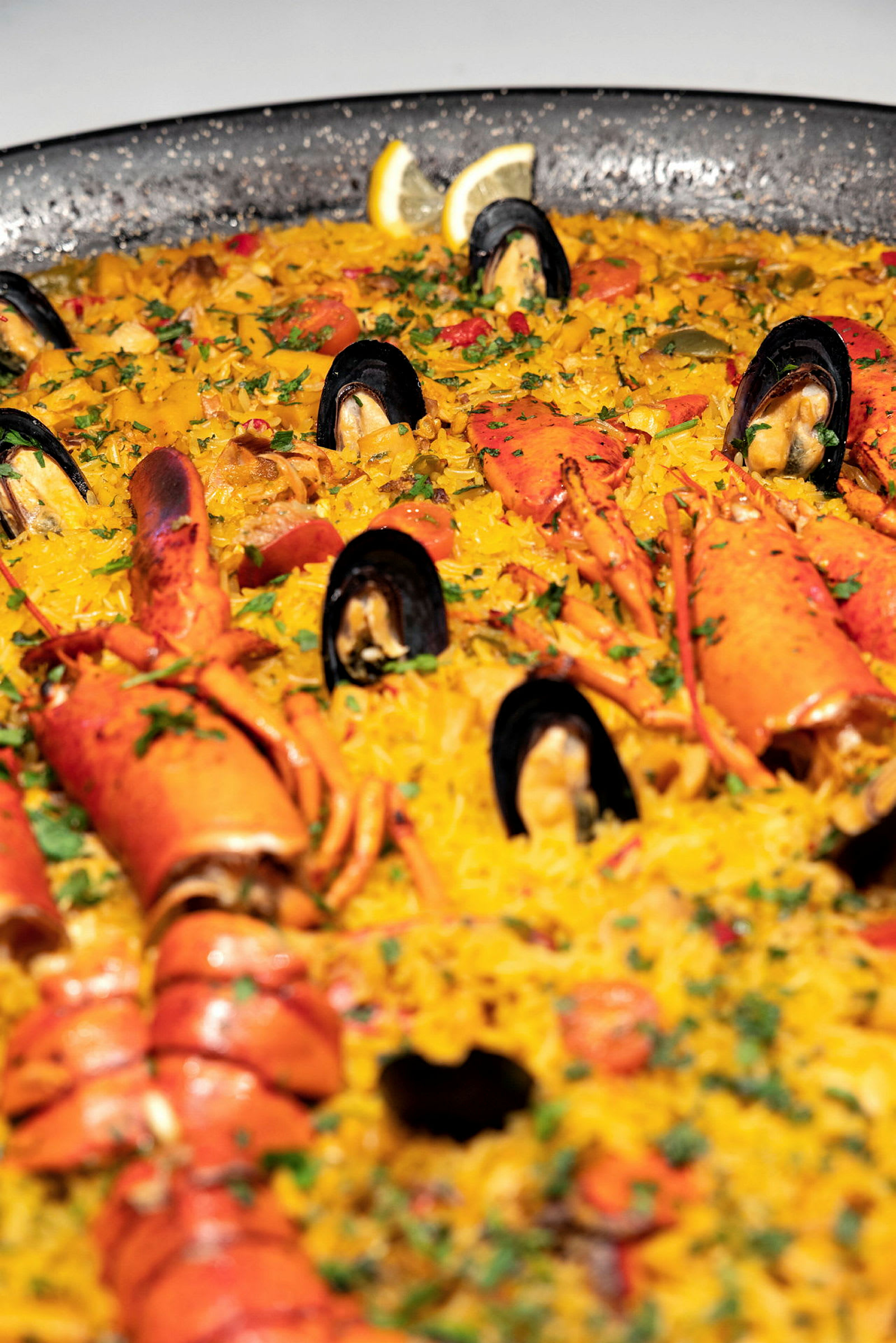 En stor paella med skaldjur, inklusive musslor och hummer, är serverad. (AI-genererad text)