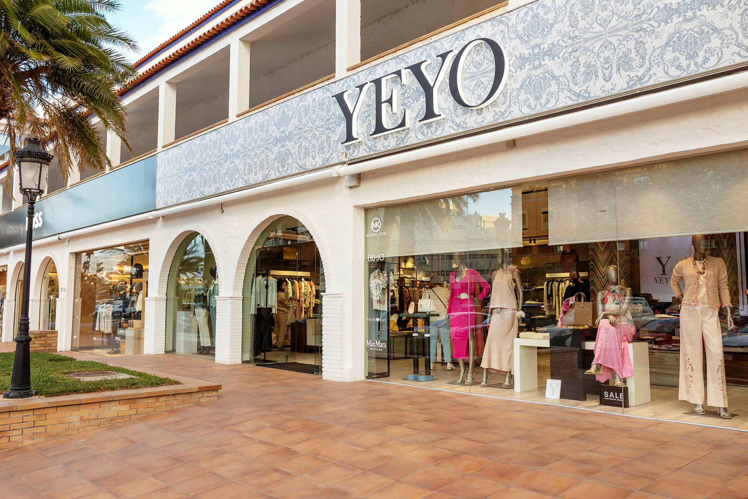 Exteriör av en butik med skylten YEYO, där kläder och dockor visas i skyltfönstret. (AI-genererad text)