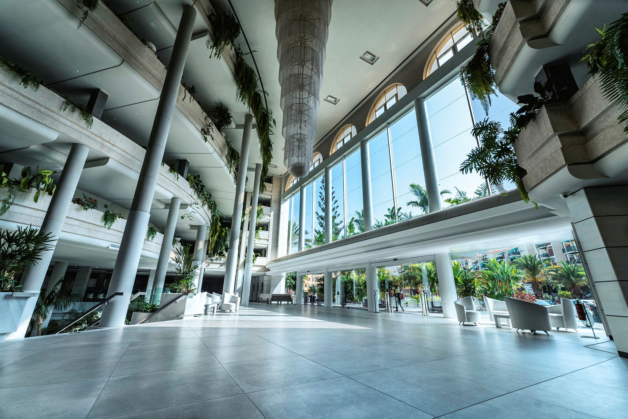 Rymlig hotellobby med moderna möbler och stora fönster med utsikt mot en grönskande trädgård. (AI-genererad text)