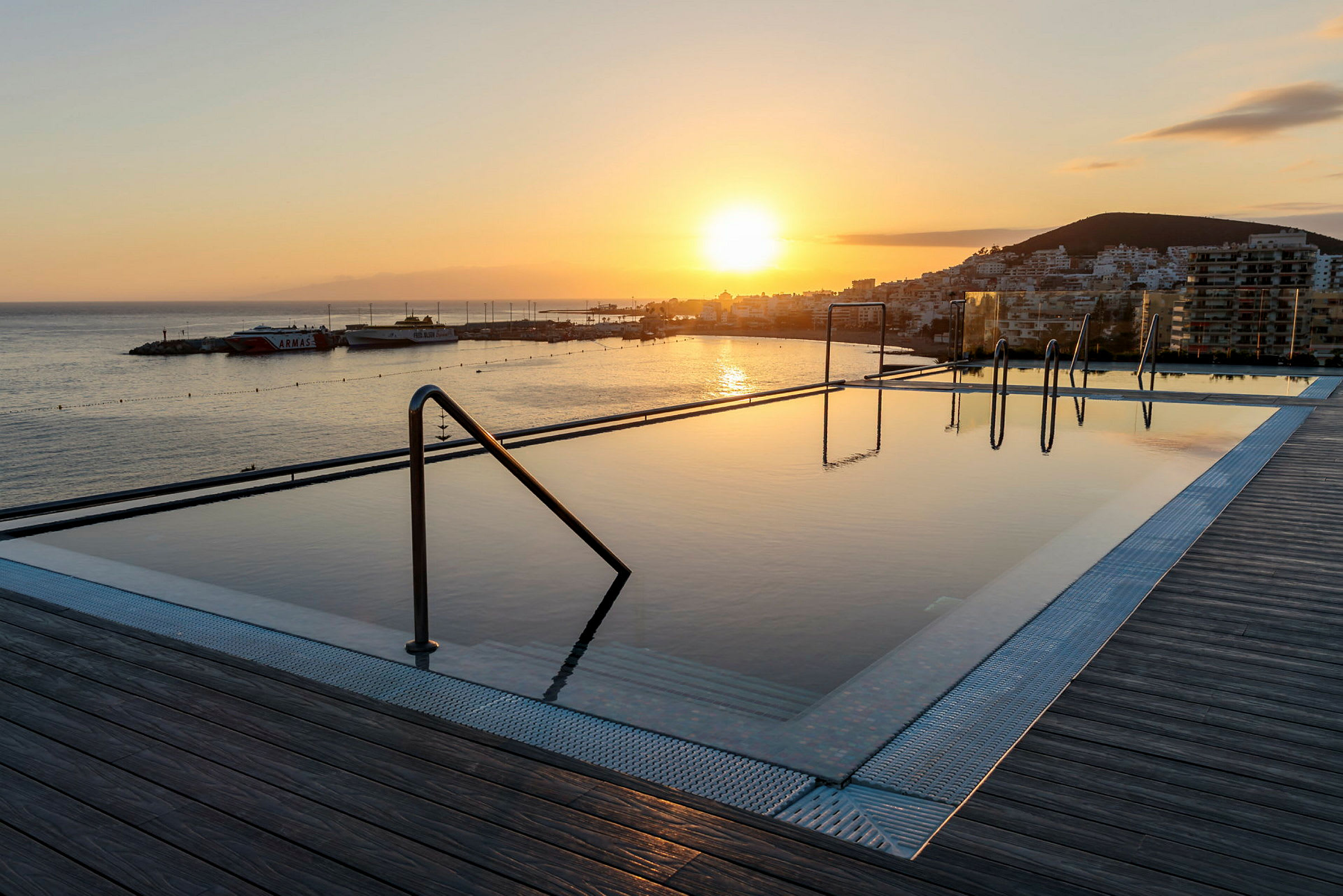 En infinitypool med utsikt över en havsutsikt vid solnedgången. (AI-genererad text)