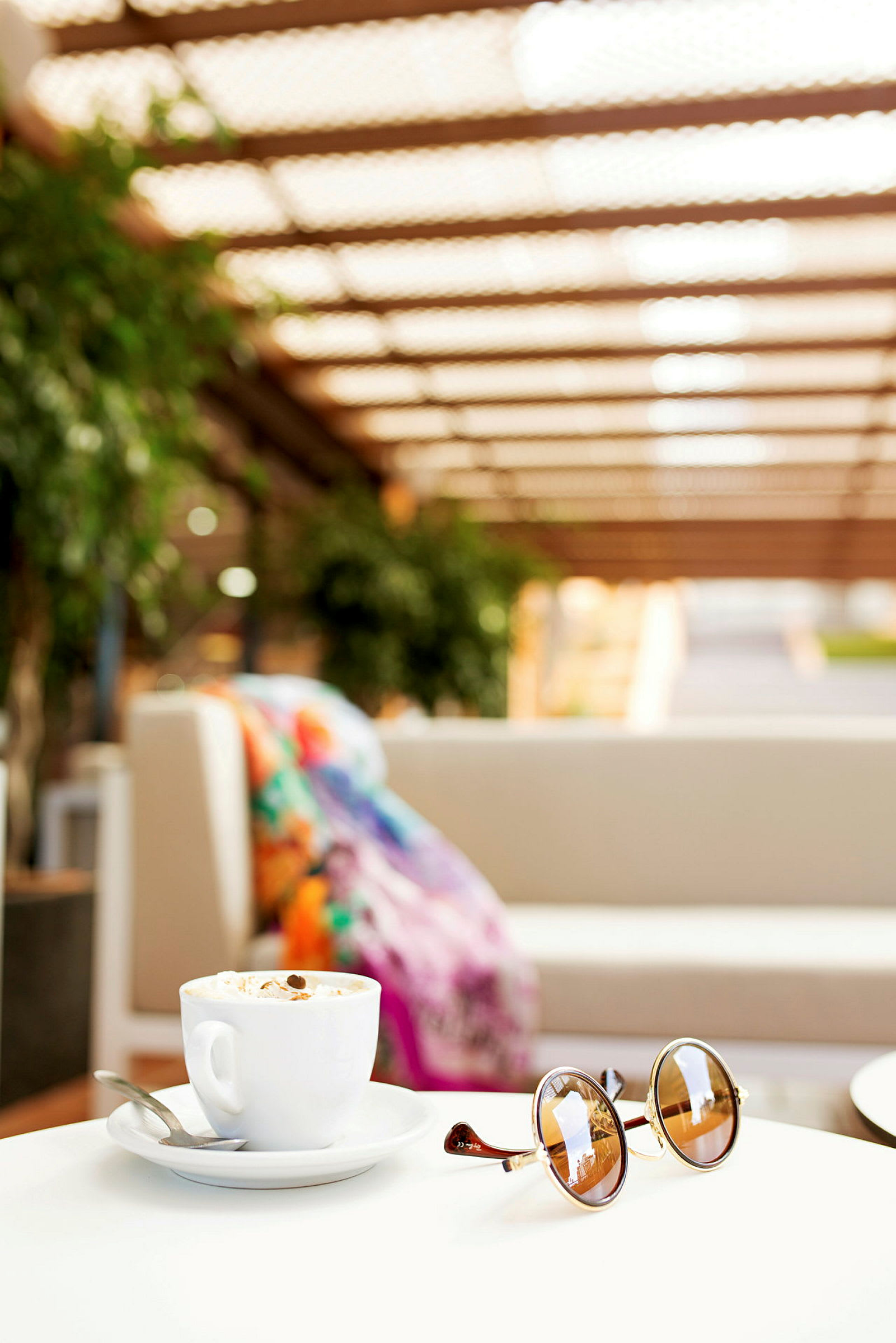 En kopp kaffe och solglasögon på ett bord med en soffa i bakgrunden. (AI-genererad text)