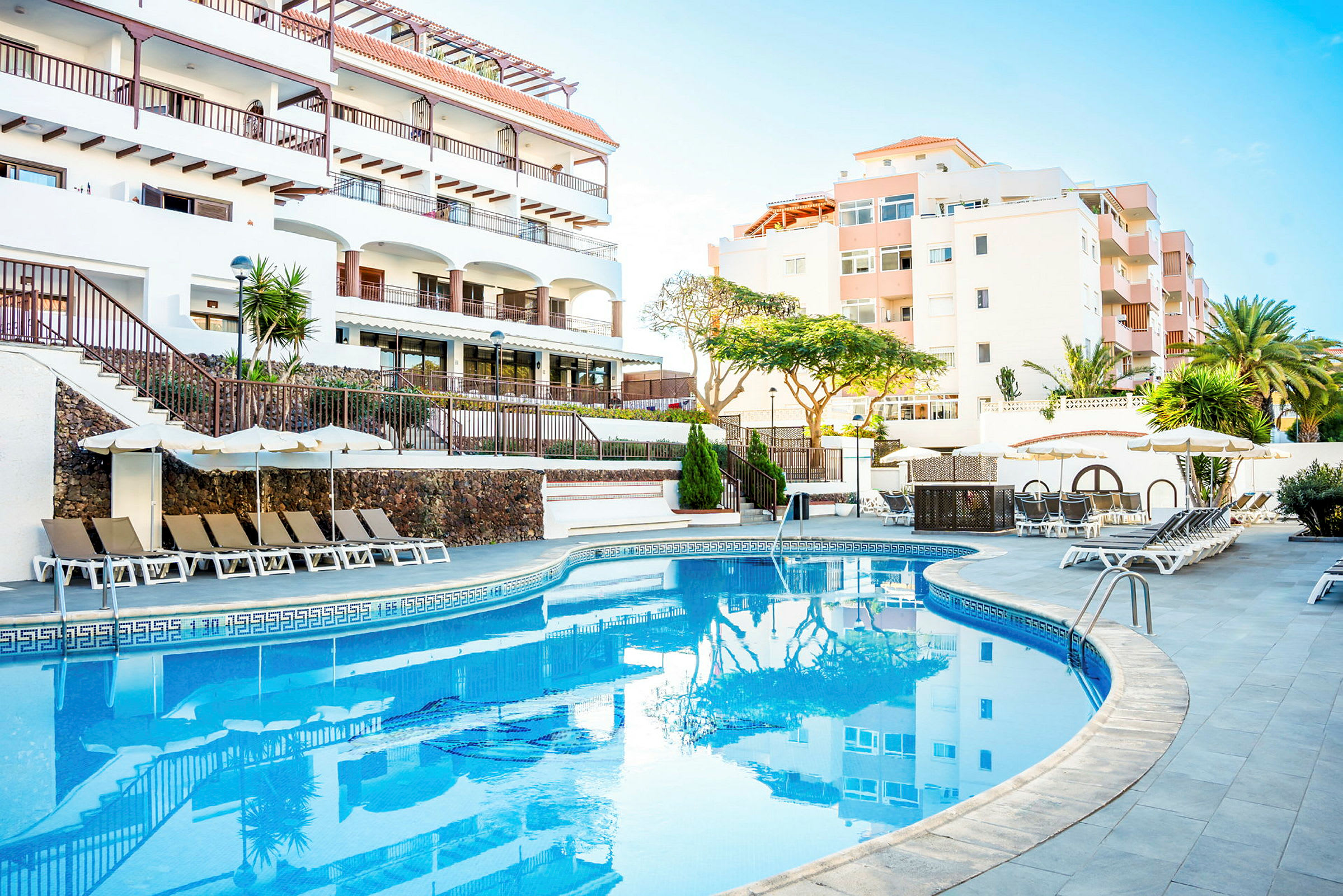 Utomhuspool med solstolar och parasoller vid ett hotell. (AI-genererad text)